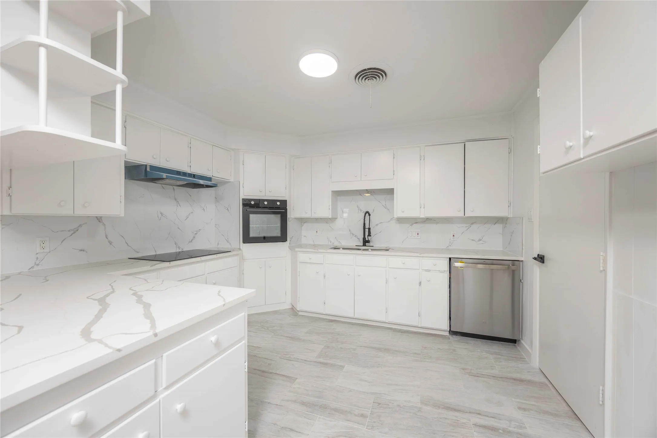 Bright kitchen featuring white cabinetry, quartz countertops with gray veining, a matching quartz backsplash, an integrated cooktop, and a built-in oven