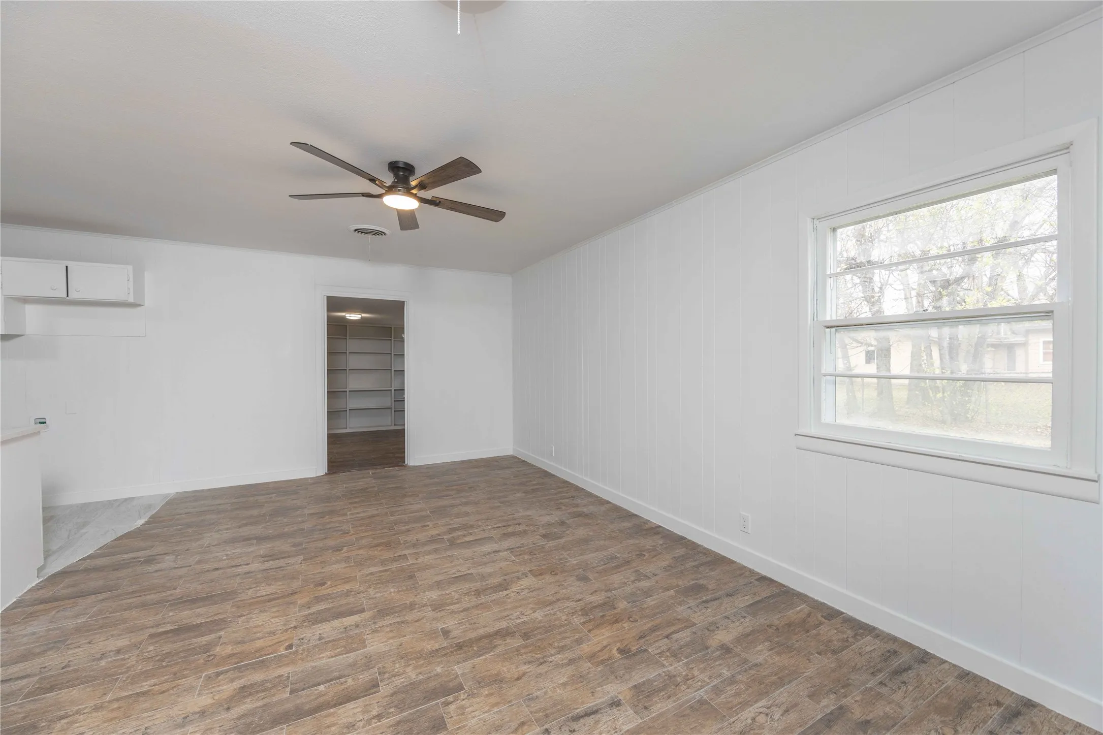 Spacious dining room with ceiling fan with integrated lighting, and a window with white trim