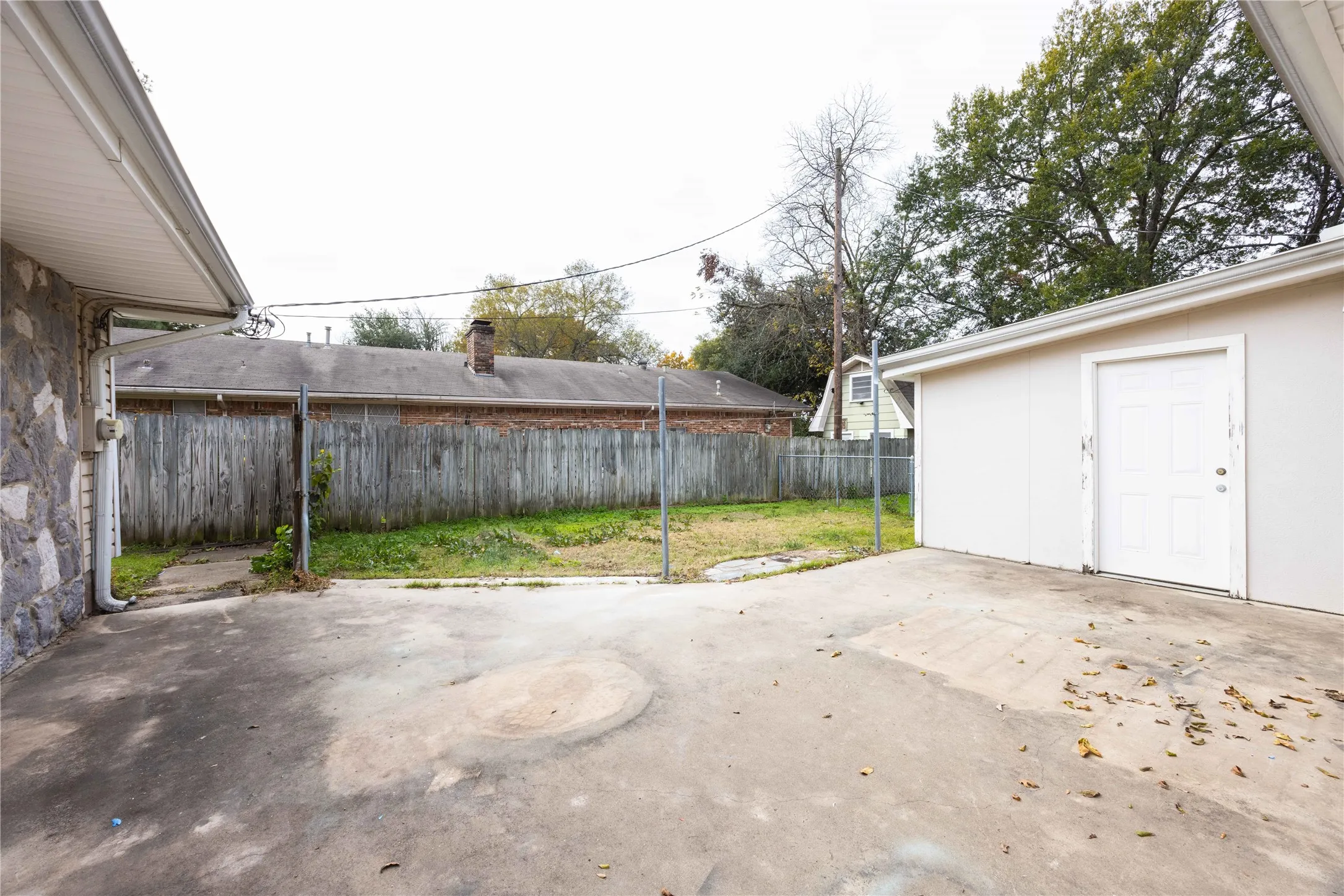 Exterior featuring a stone-clad wall, white painted siding, and concrete paving