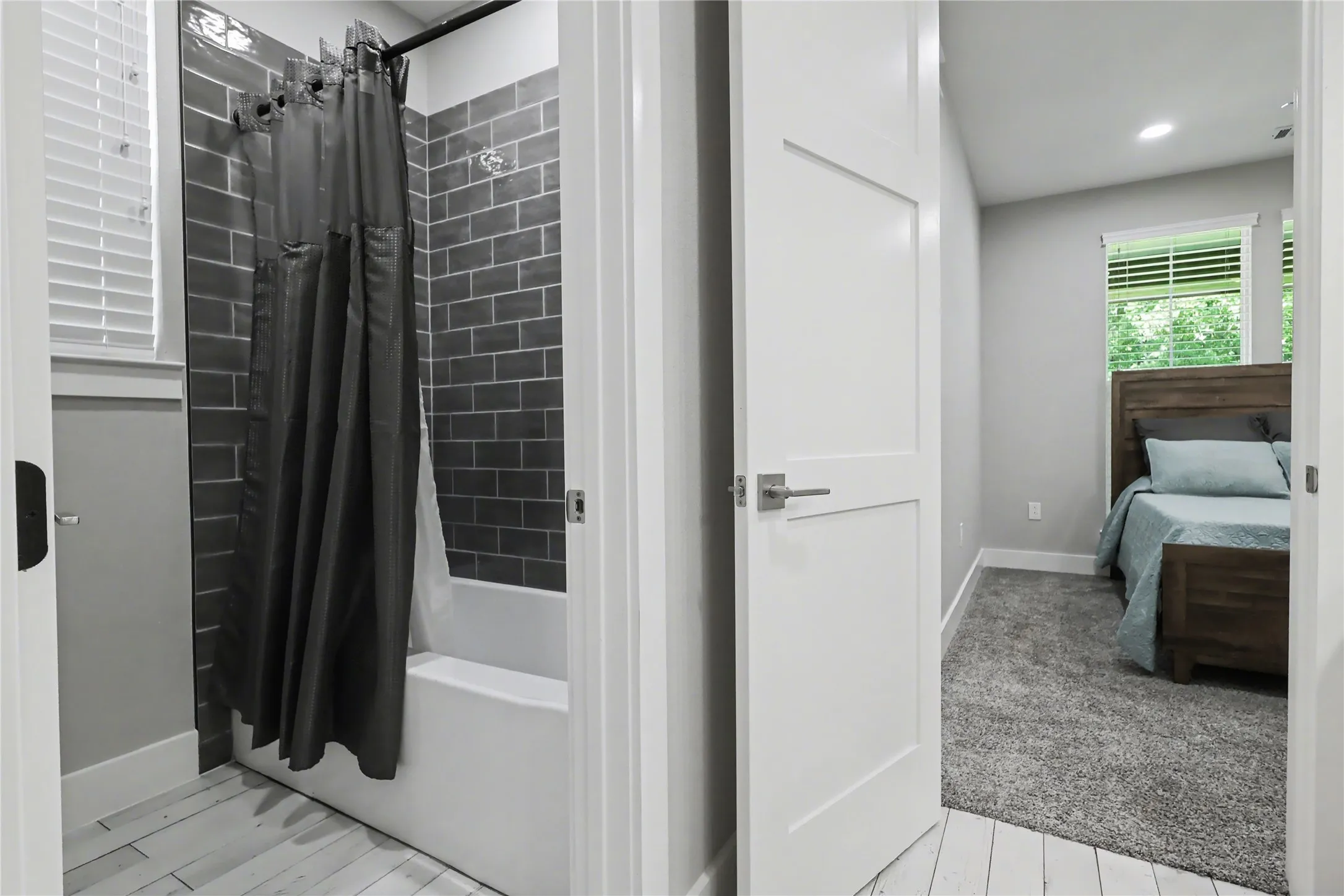 Bathroom featuring subway tile shower surround and light wood-finish flooring