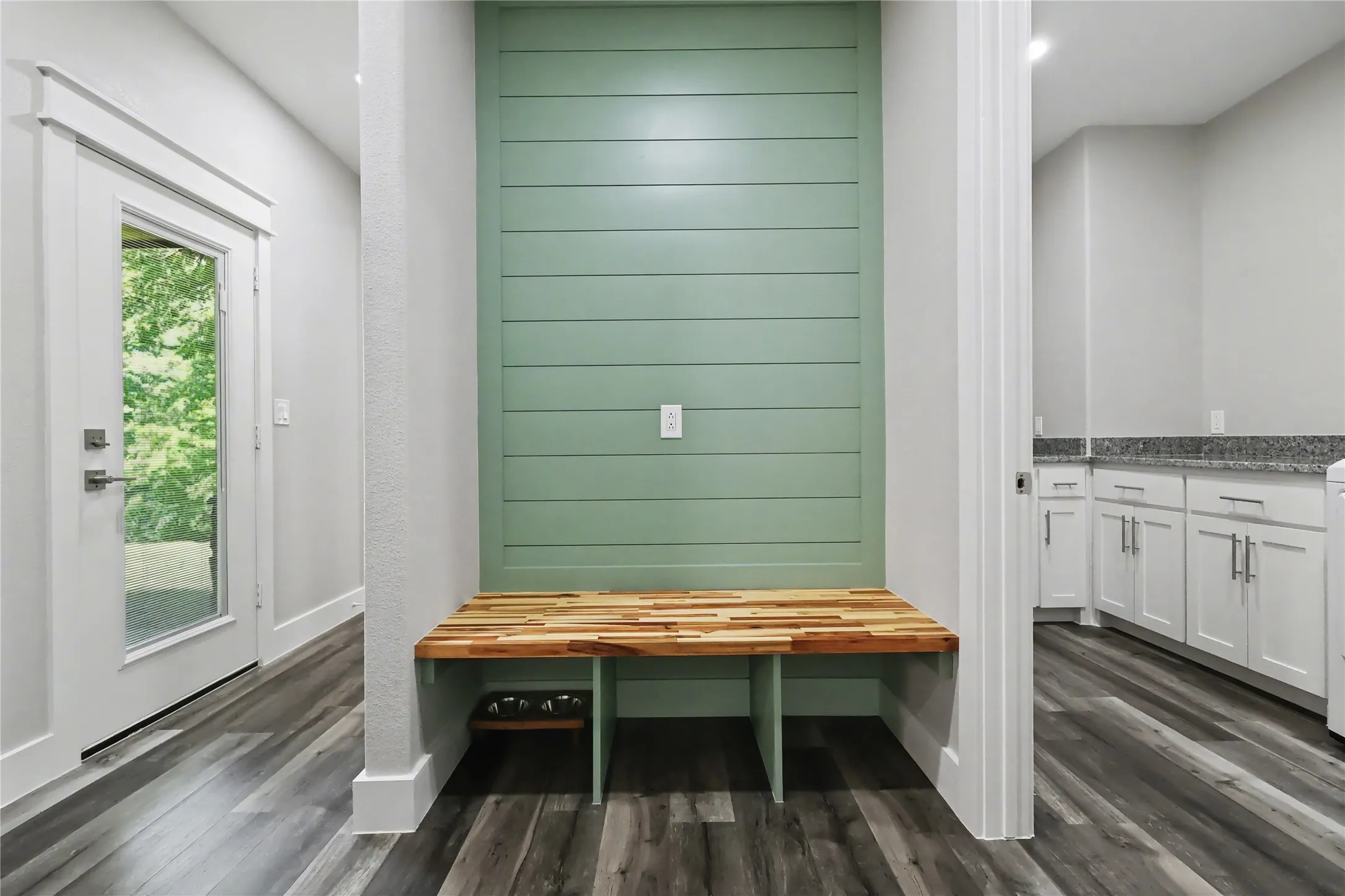 Built-in bench with a natural wood-finish top and green shiplap accent wall