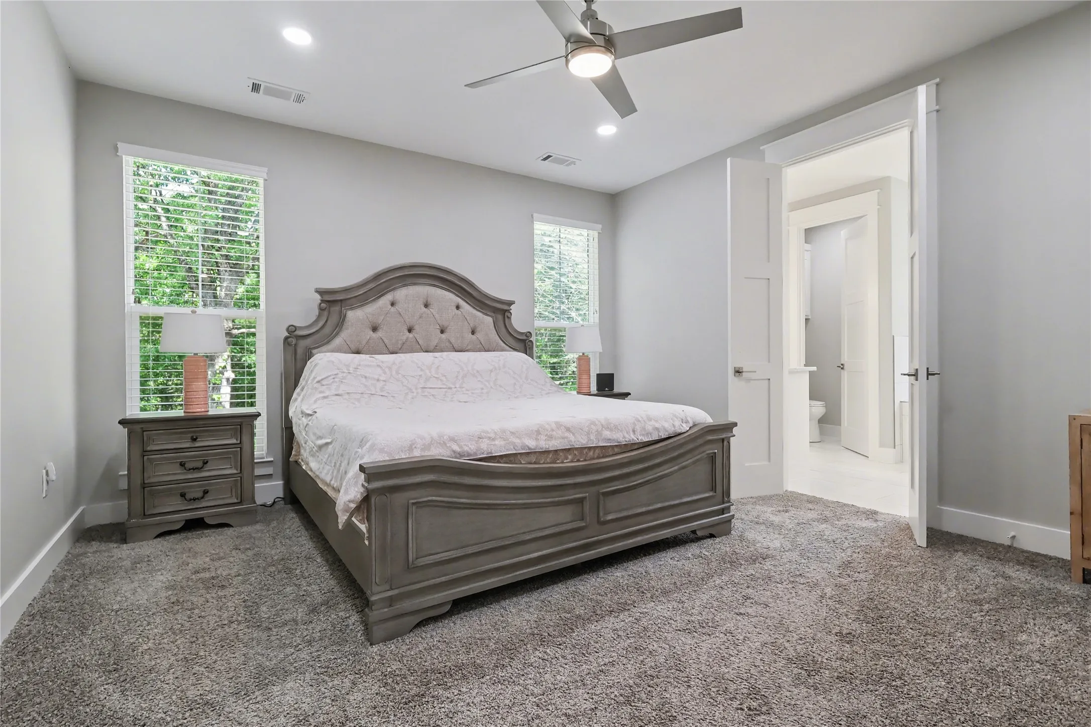 Spacious carpeted room featuring two large windows with blinds, recessed lighting, and a ceiling fan
