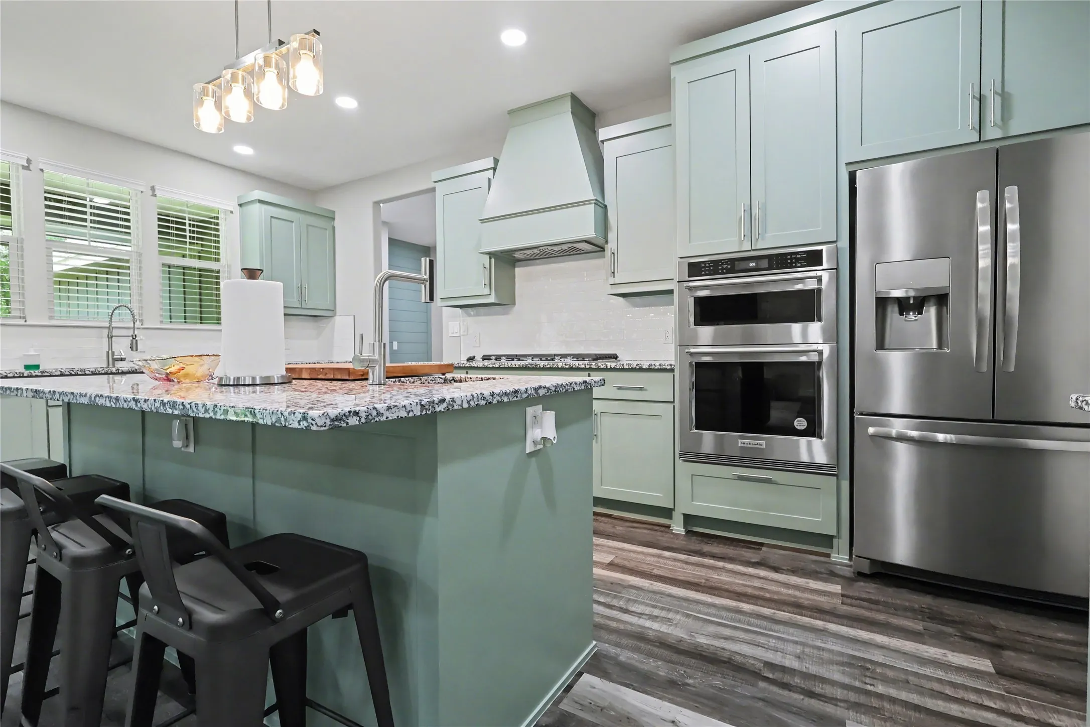 Kitchen featuring a large central island with seating, a patterned countertop, and a gooseneck faucet