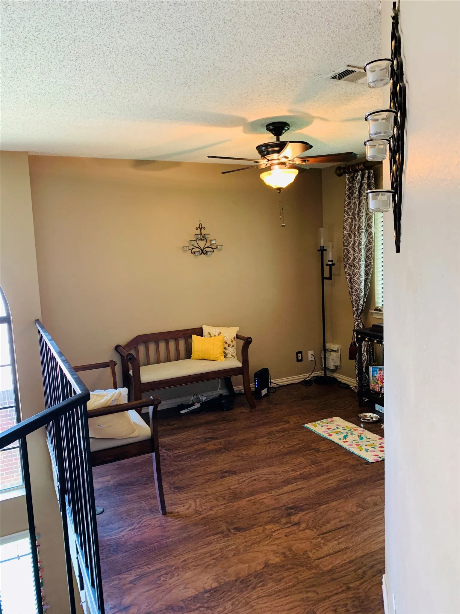 Upper-level space featuring wood-finish flooring, a ceiling fan with integrated lighting, and a metal railing