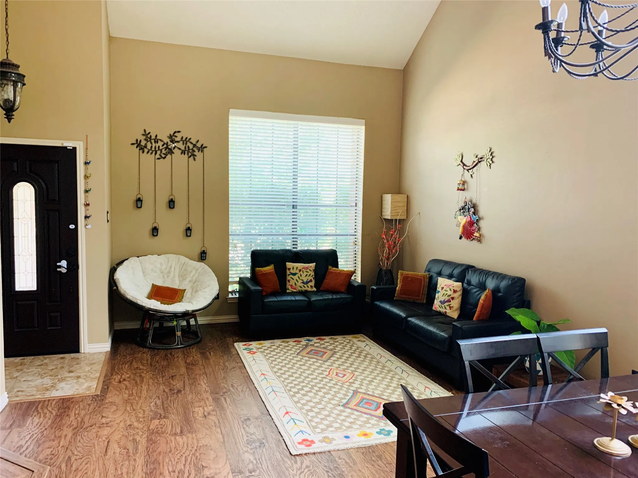 Entry area featuring a dark paneled door with an arched glass insert, high vaulted ceilings, and wood-finish flooring