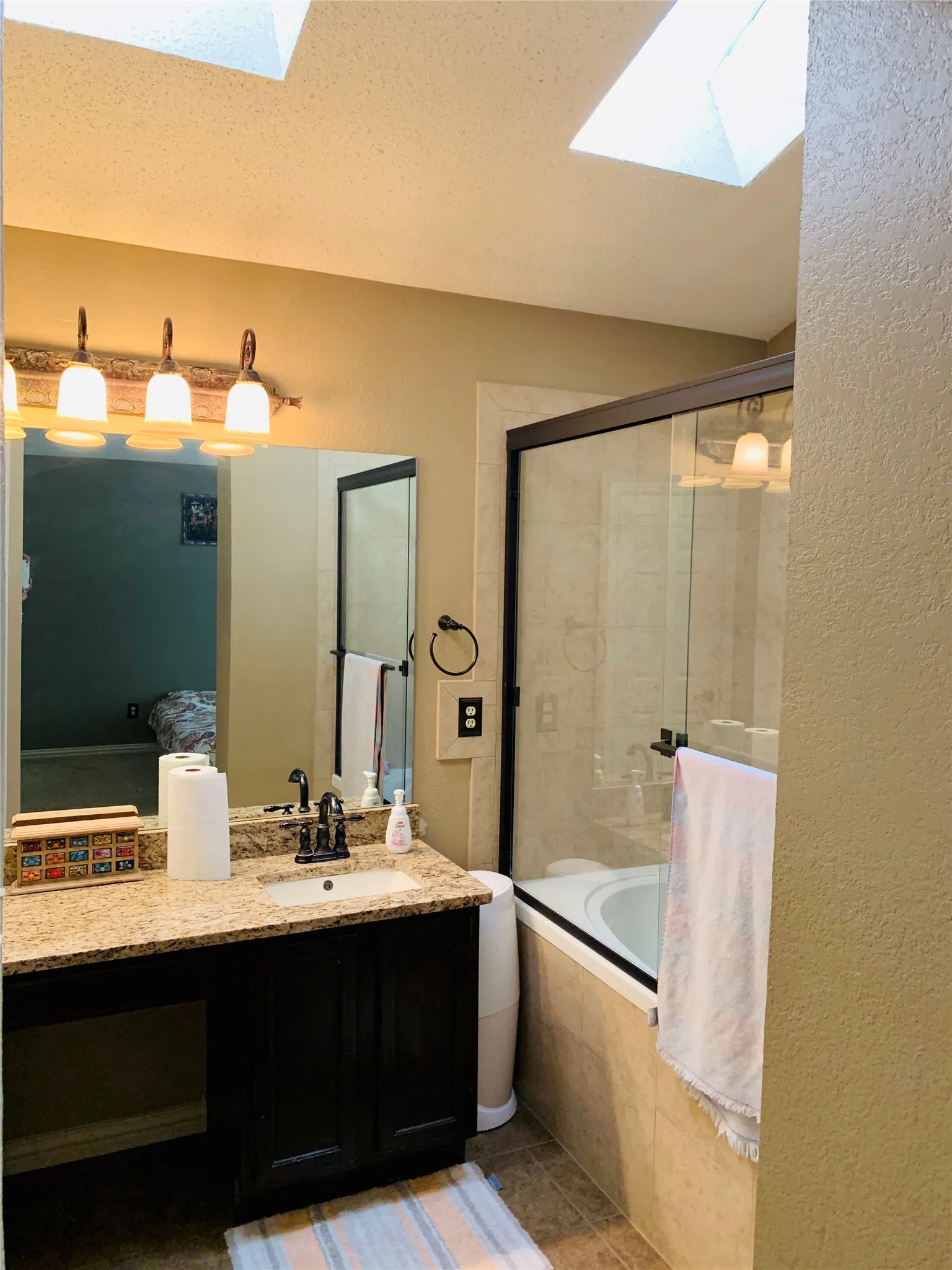 Bathroom featuring a vanity with a granite-finish countertop, undermount sink, and dark wood cabinetry