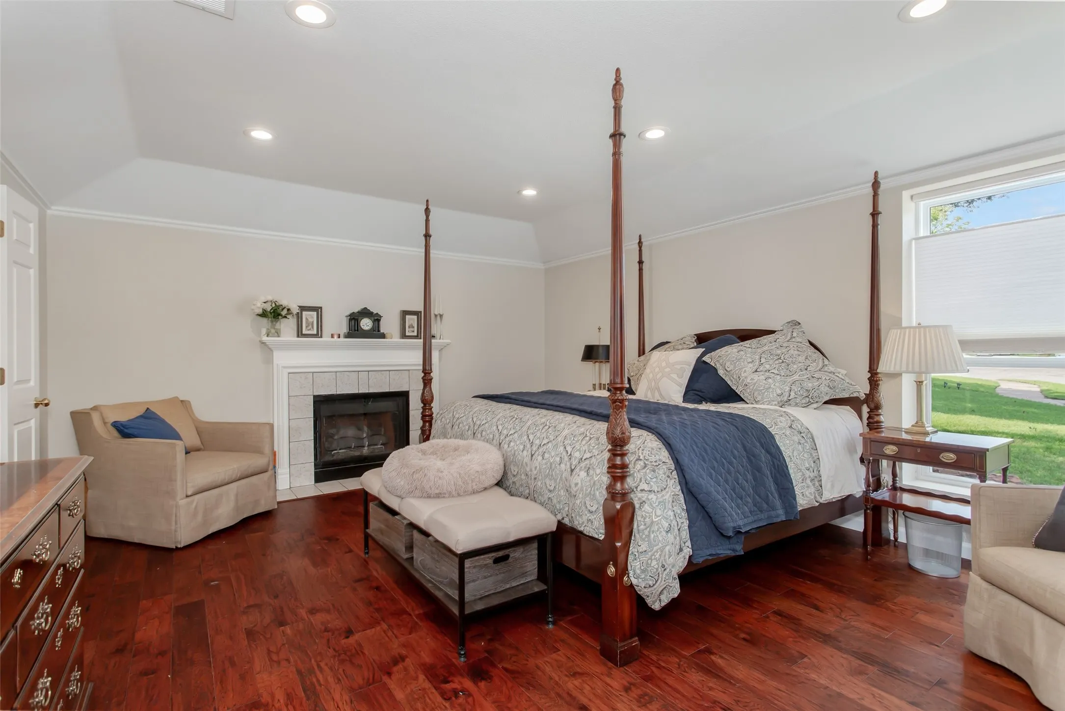 Spacious room featuring rich wood-finish flooring, a fireplace with a tiled surround and mantel, and recessed lighting