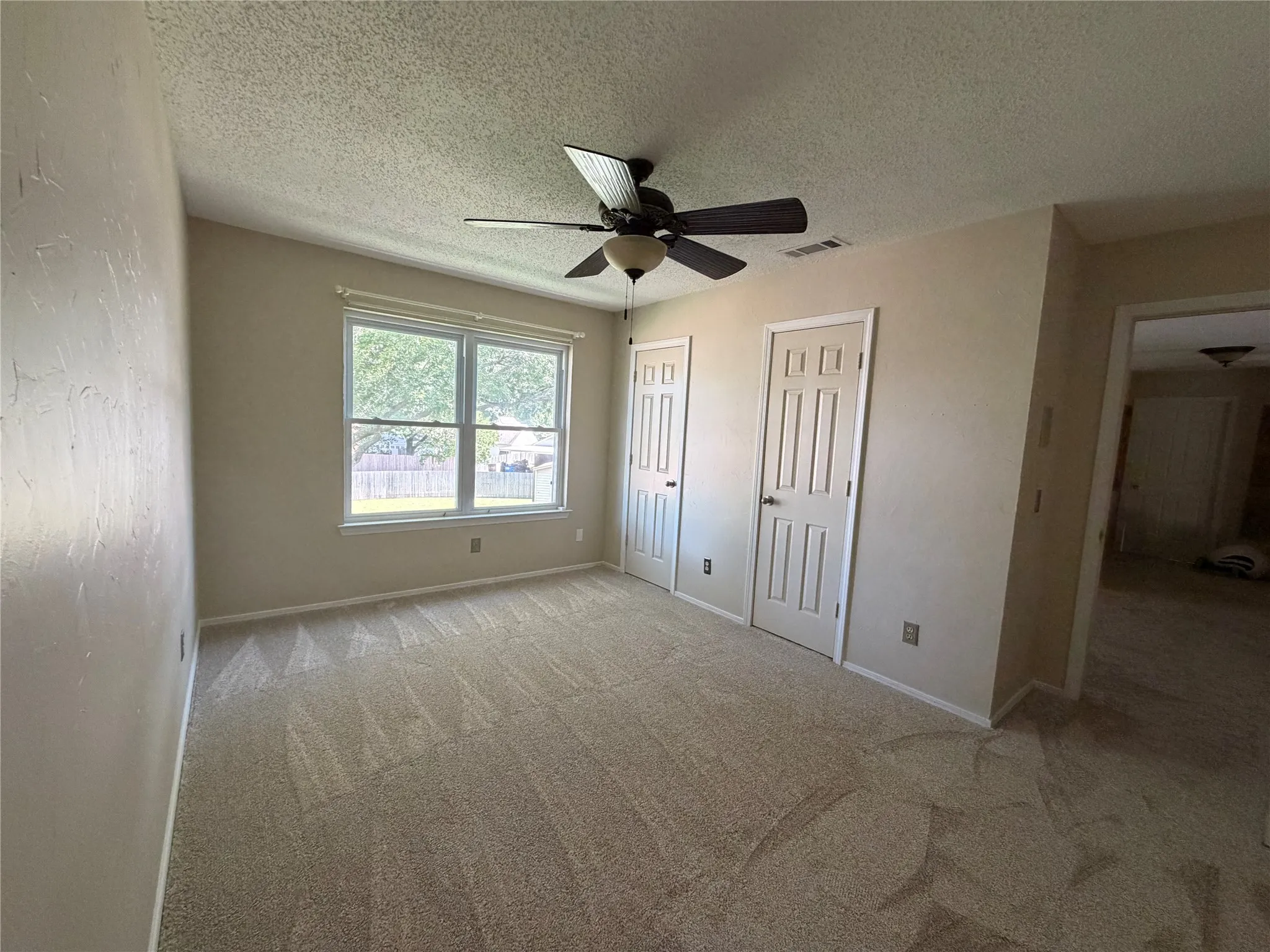 Carpeted room featuring a ceiling fan, a double window, and two paneled doors