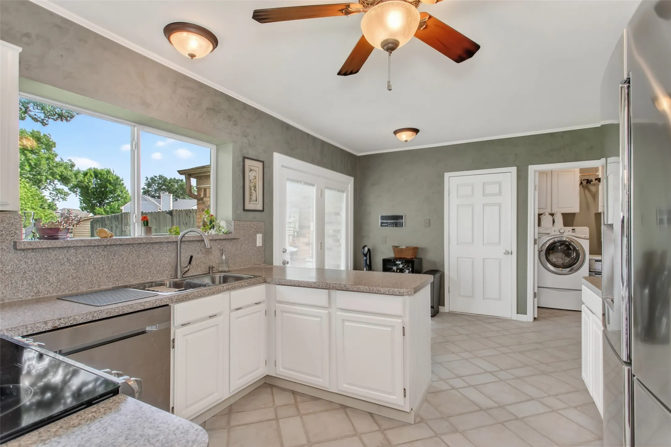 Kitchen featuring white cabinetry, light-toned countertops, a stainless steel dishwasher, and a double basin sink
