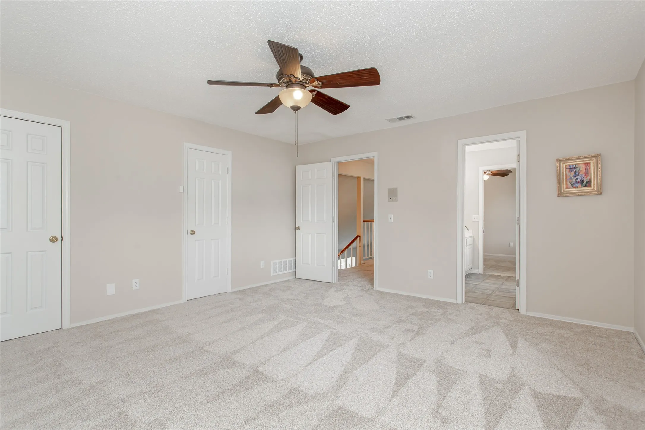 Spacious room featuring neutral carpet flooring, light-toned walls, and a ceiling fan with integrated lighting