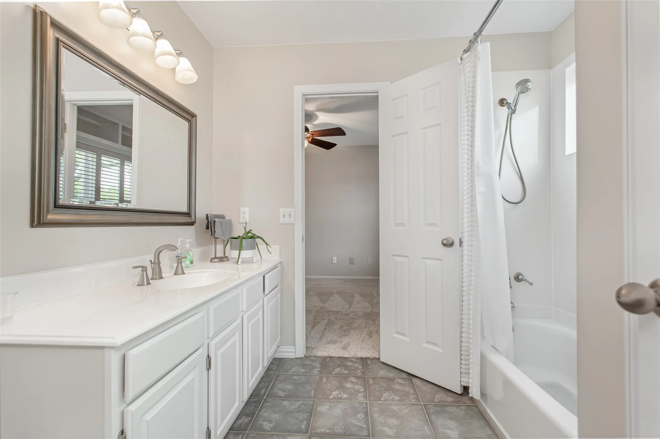 Bathroom vanity with dual sinks, white cabinetry, and a countertop