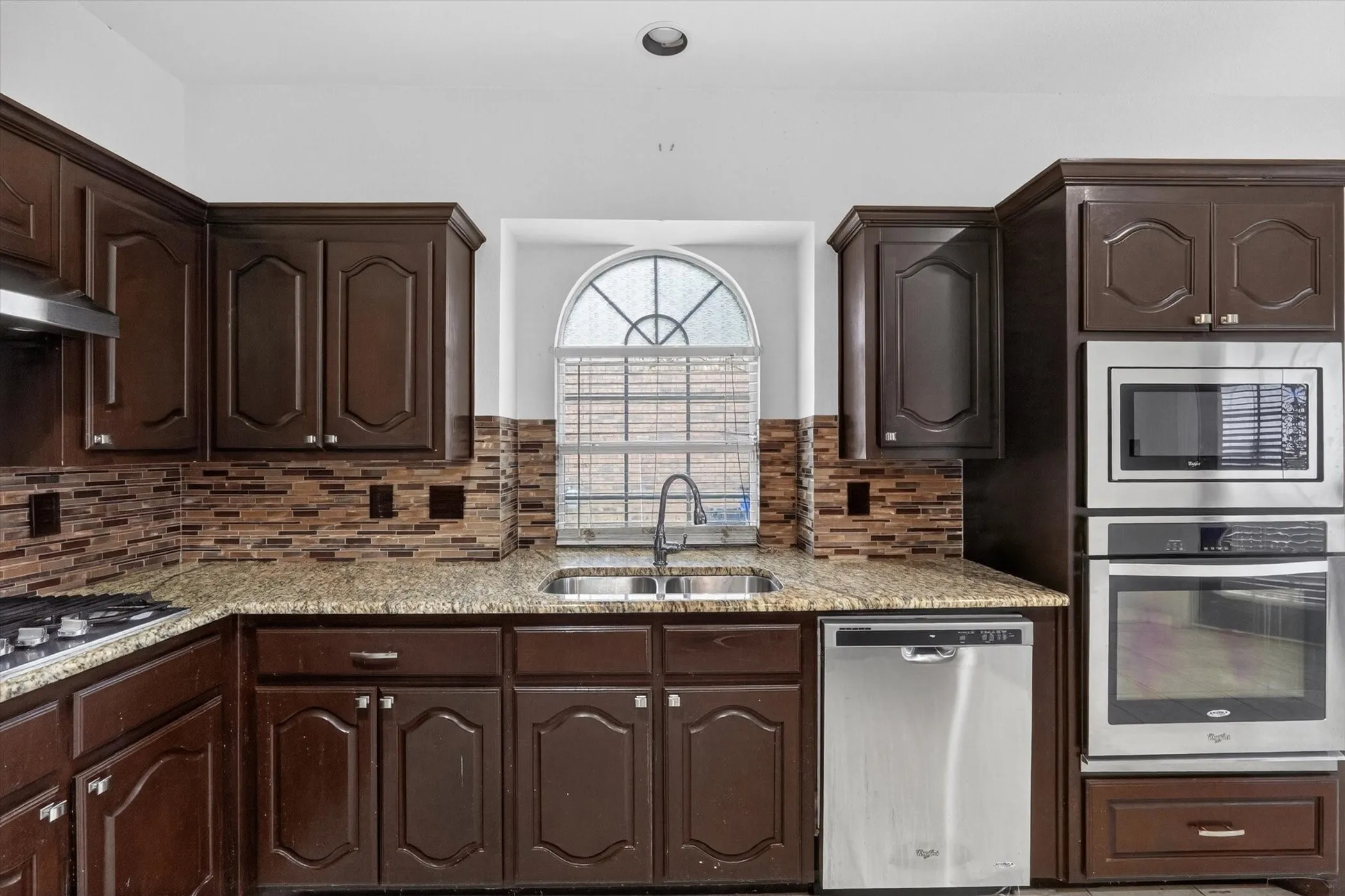 Kitchen featuring wood cabinetry, granite countertops, and a mosaic tile backsplash