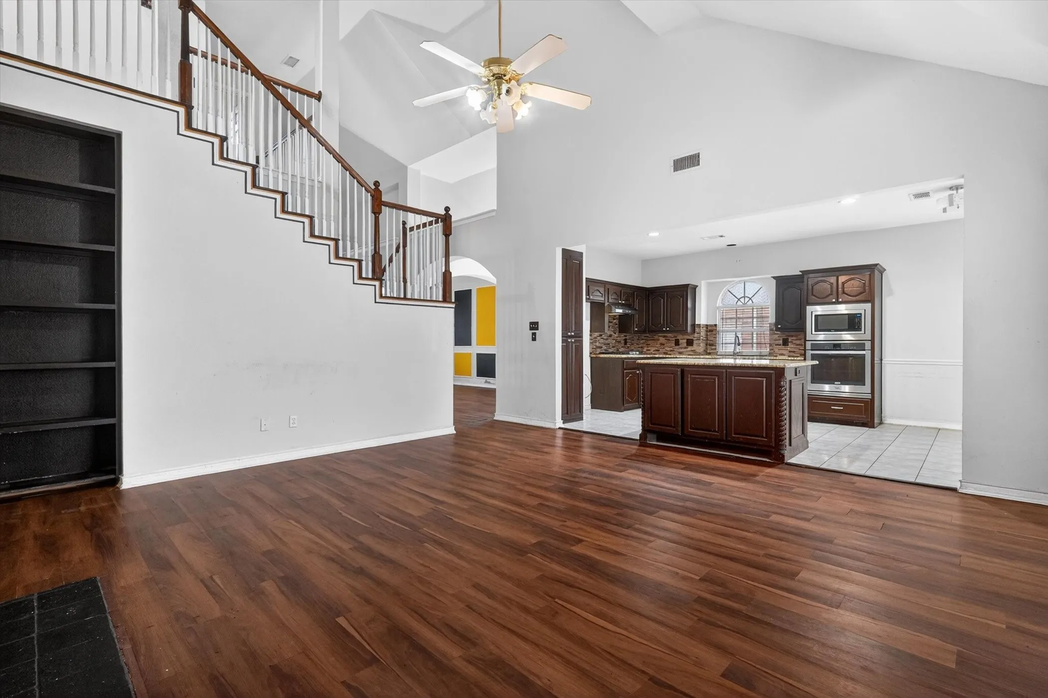 Expansive living area featuring vaulted ceilings, rich wood-finish flooring, and a built-in bookshelf