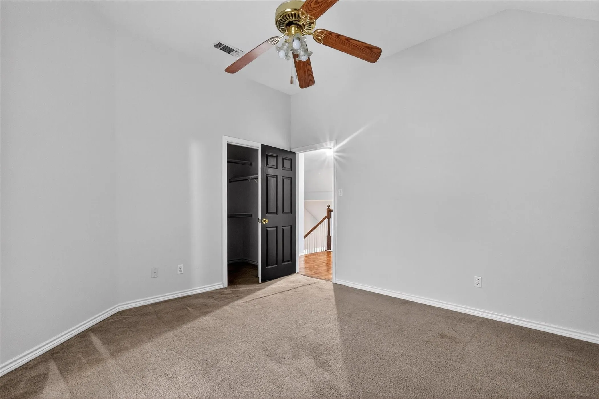 Carpeted room with vaulted ceilings and a ceiling fan