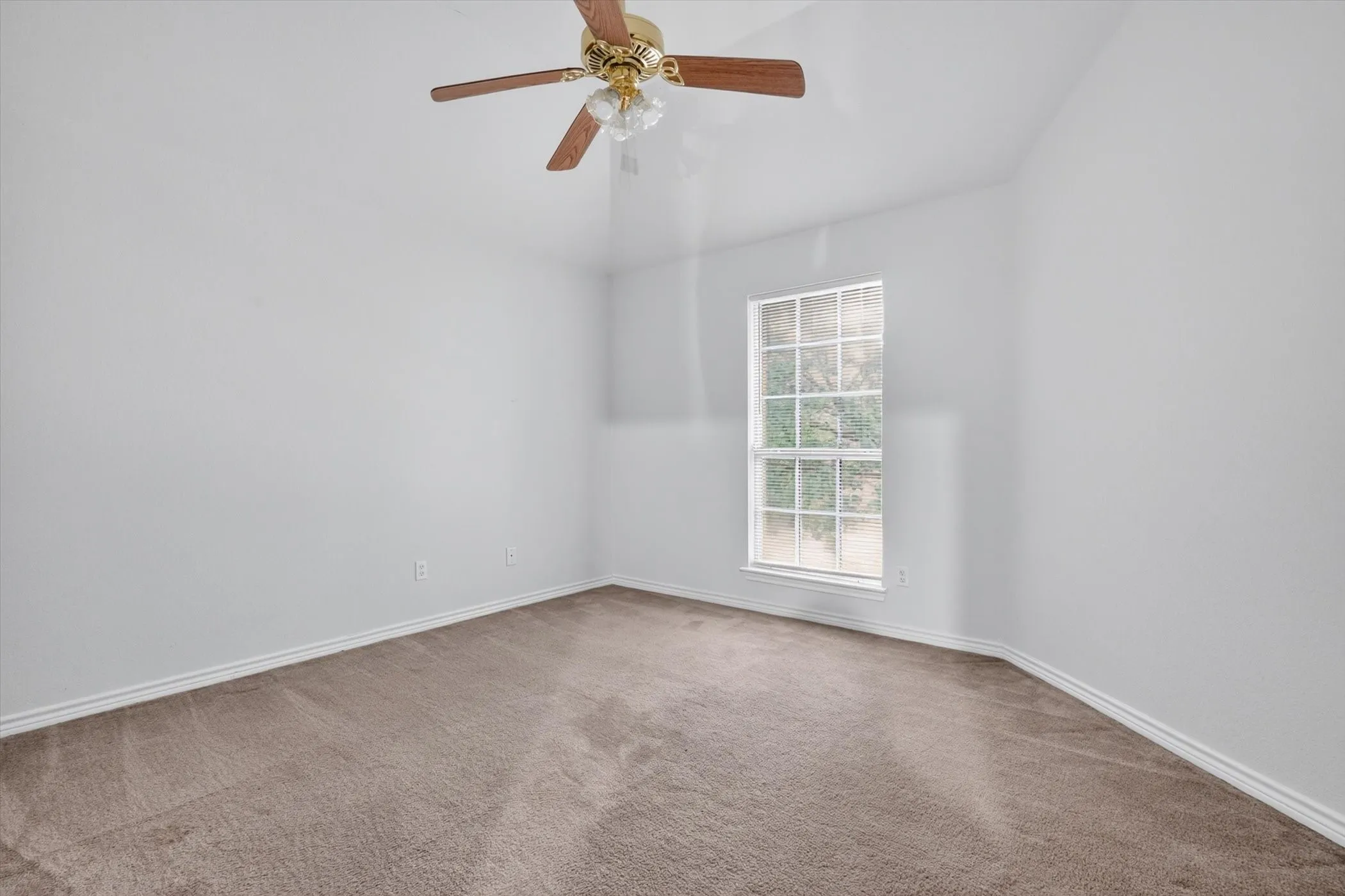 Carpeted interior space featuring a single window with grids, white trim, and a ceiling fan