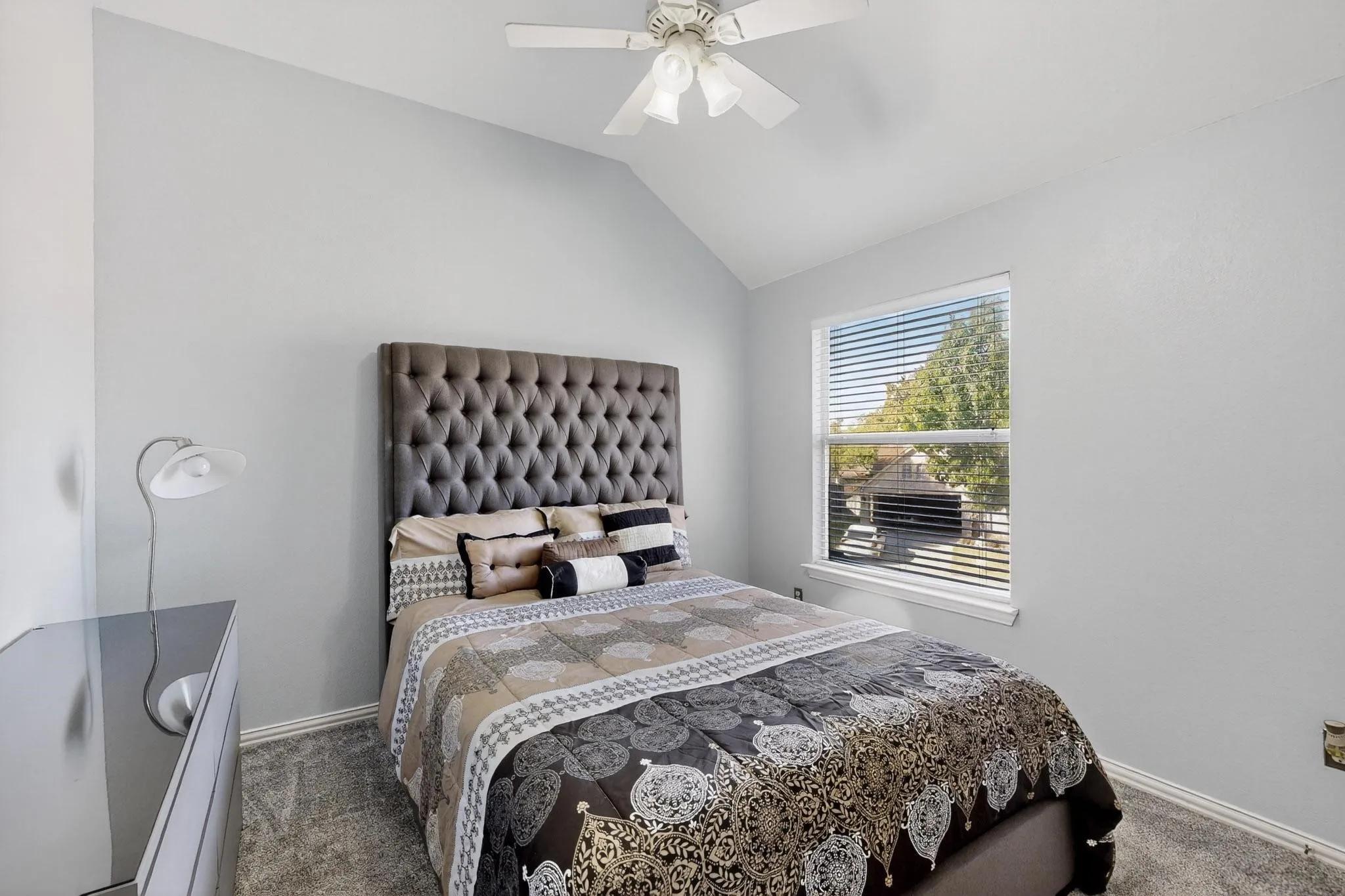 Bedroom featuring vaulted ceilings, a ceiling fan, a window with horizontal blinds, and neutral-toned walls