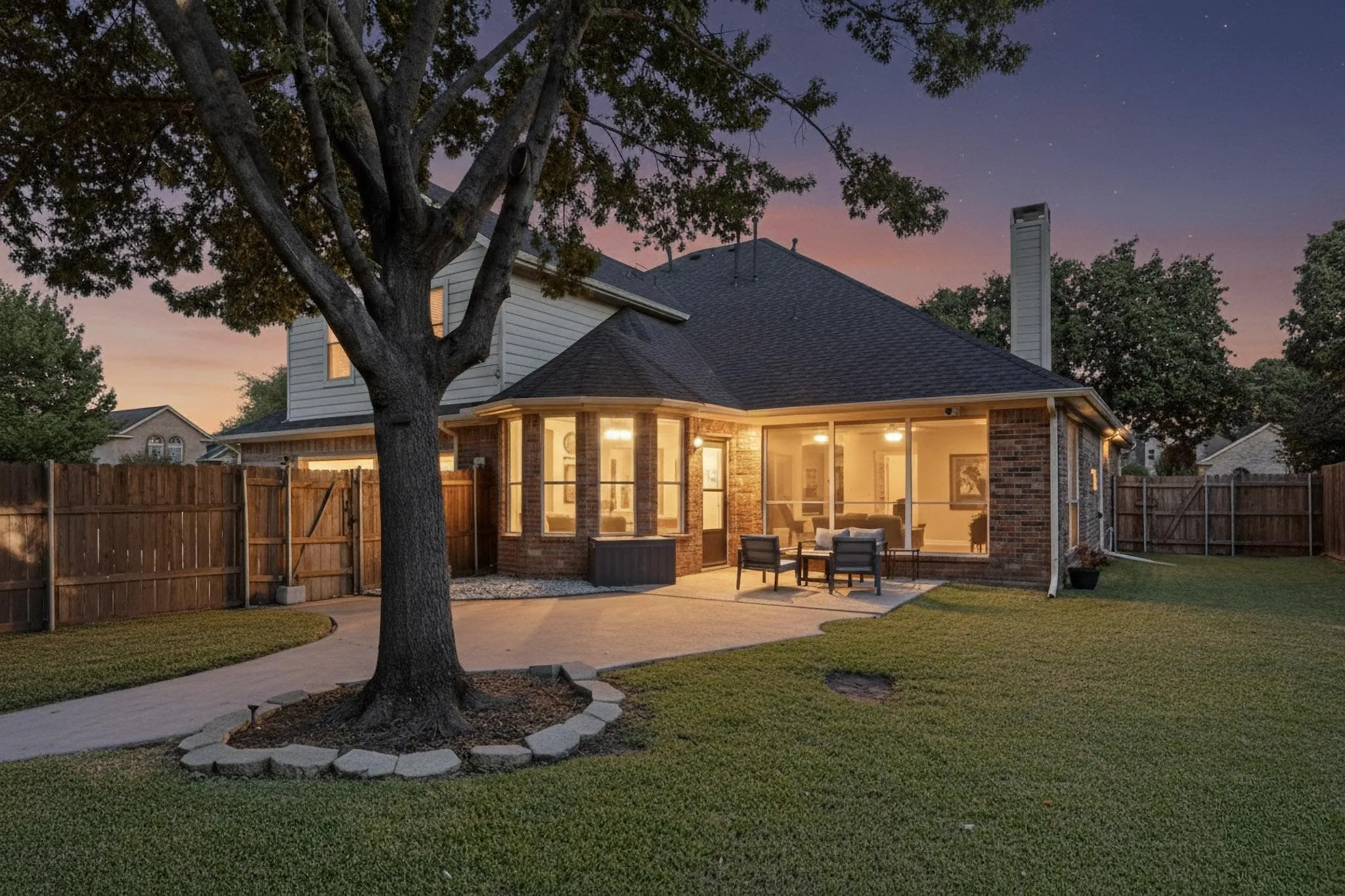 Spacious backyard featuring a concrete patio, expansive lawn, and mature trees