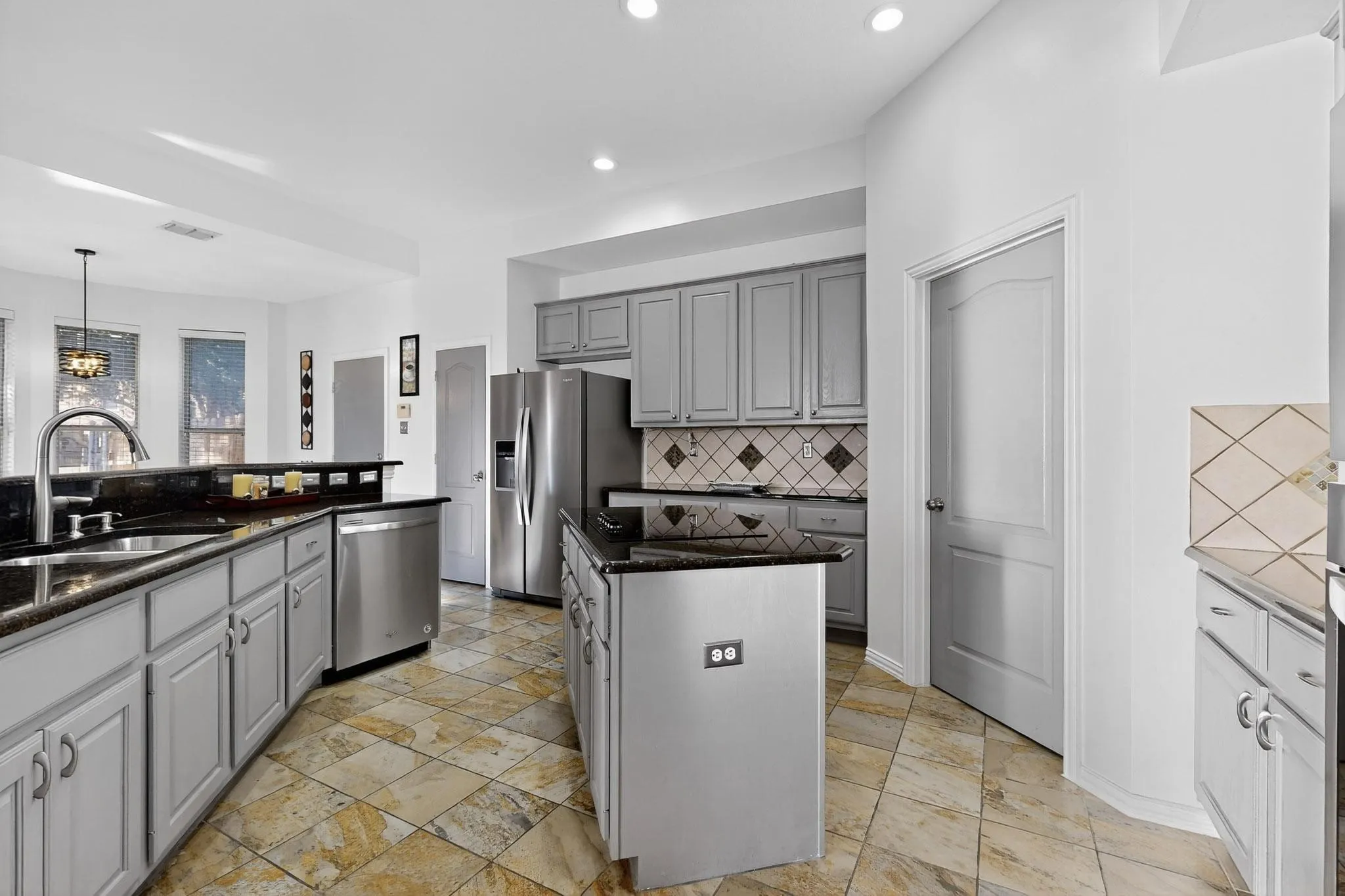 Kitchen featuring grey cabinetry, stainless steel appliances, dark countertops, and tile flooring