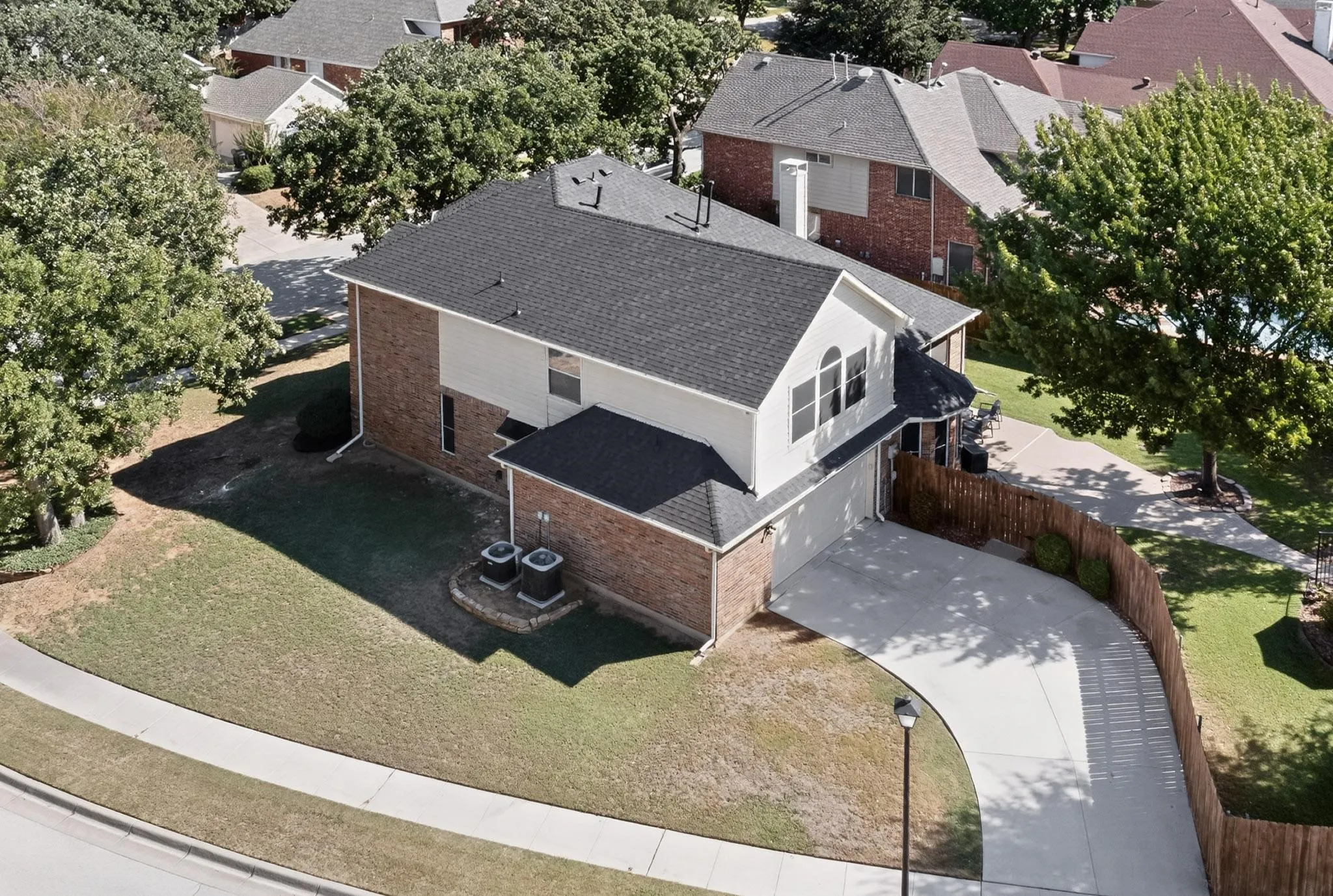 Two-story residence featuring a brick and siding exterior, a dark shingle roof, and an arched window detail