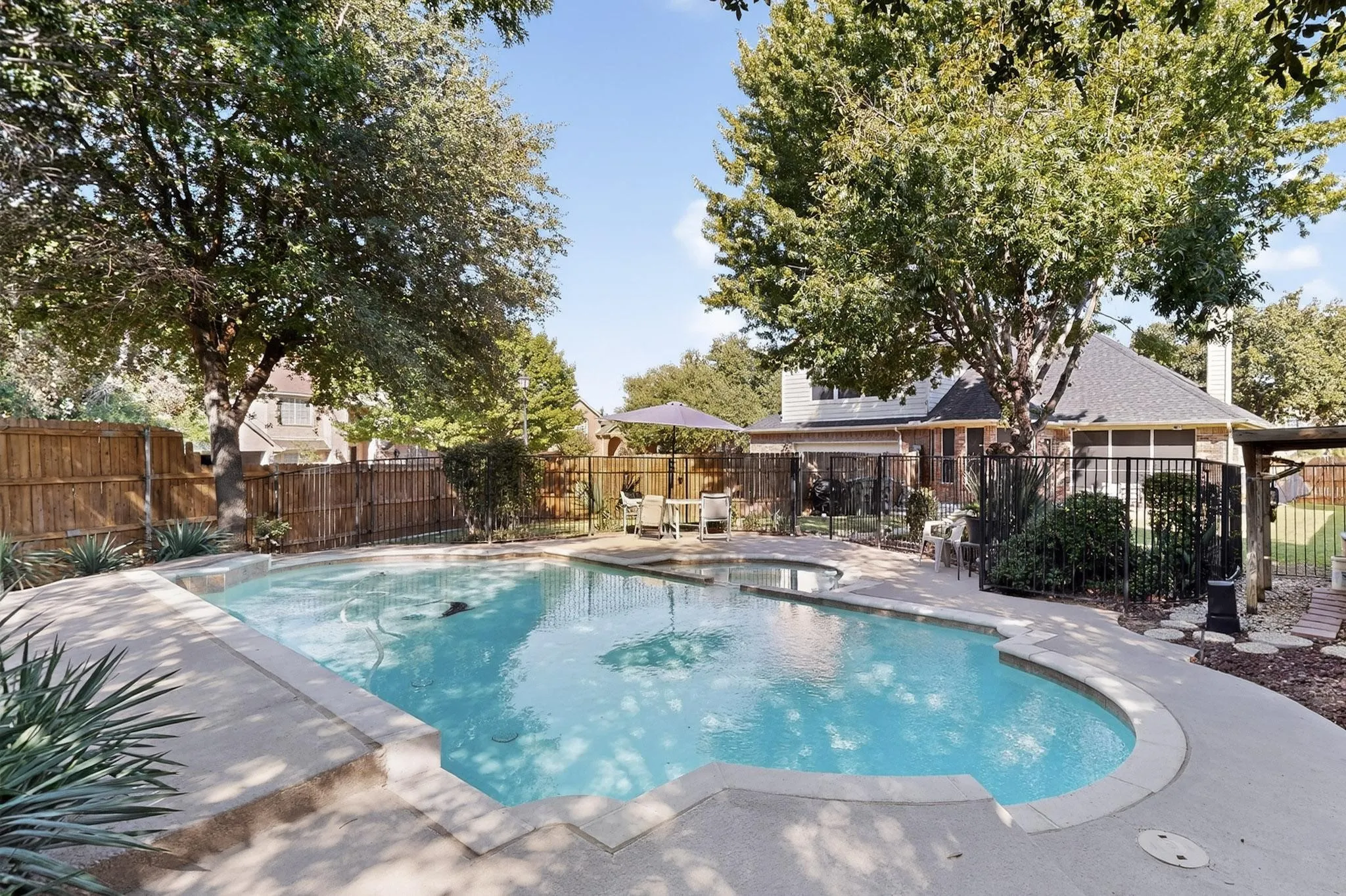 In-ground swimming pool with integrated spa and surrounding concrete decking