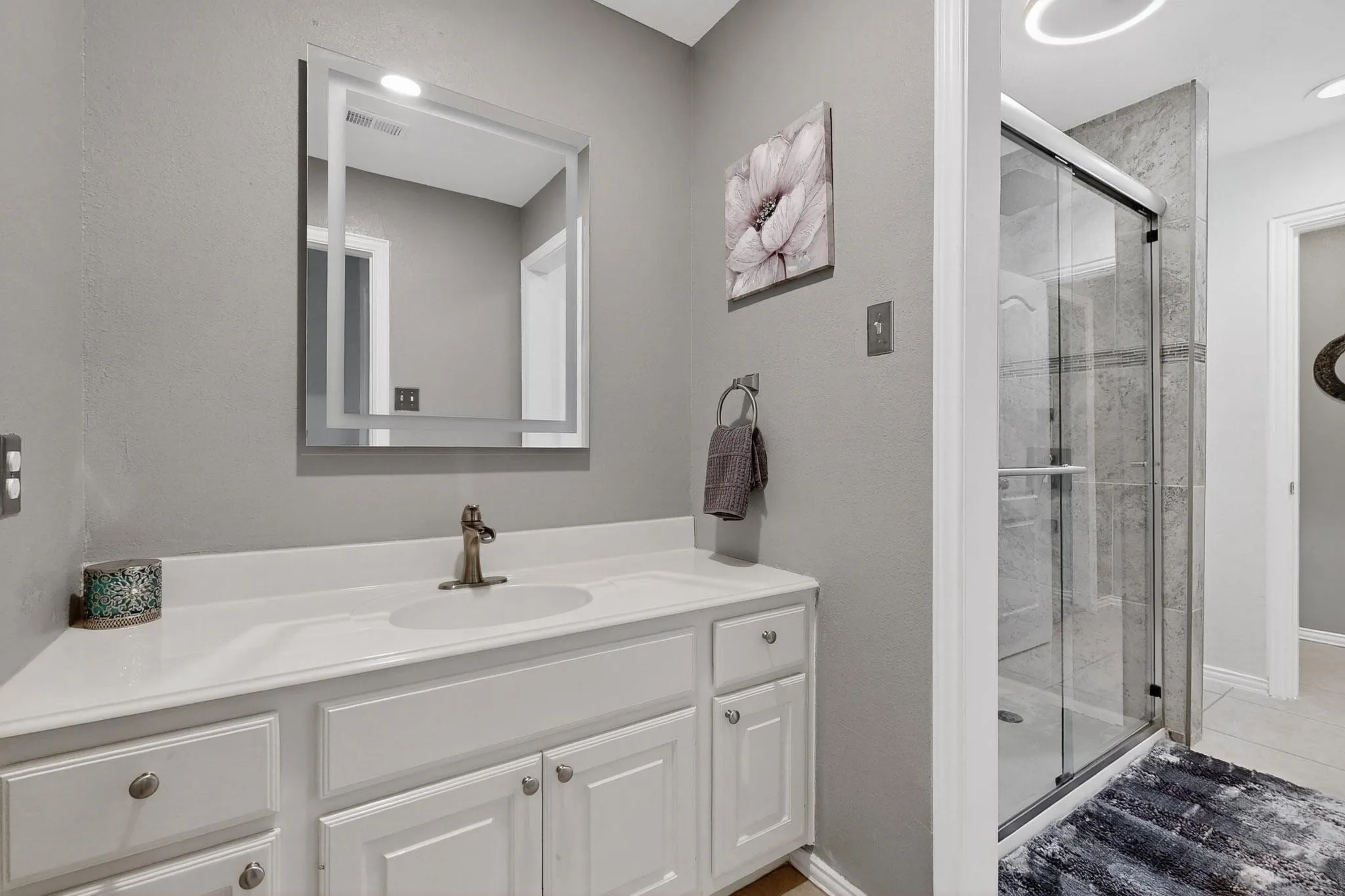 Bathroom featuring a single vanity with white cabinetry, a white countertop, and an integrated sink