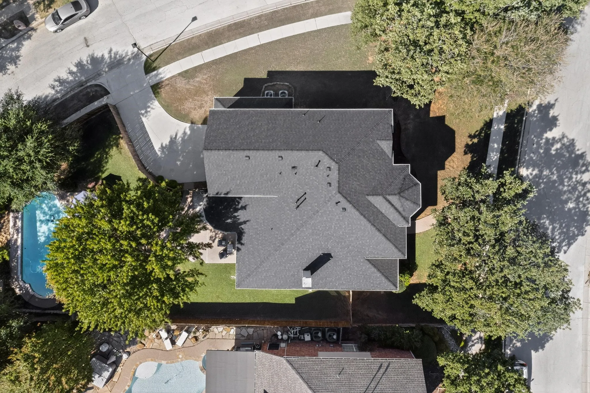 Property featuring a dark shingle roof, a spacious driveway, and a private swimming pool