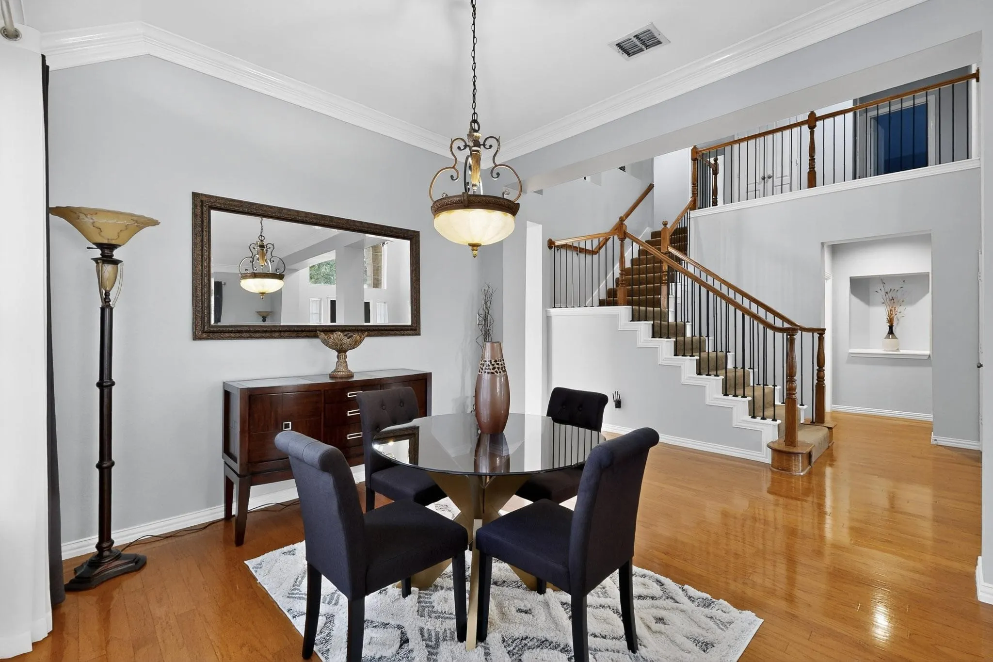 Open-concept dining area featuring wood-finish flooring, a multi-level staircase with wood railings and black metal balusters, and a recessed wall niche with built-in shelving
