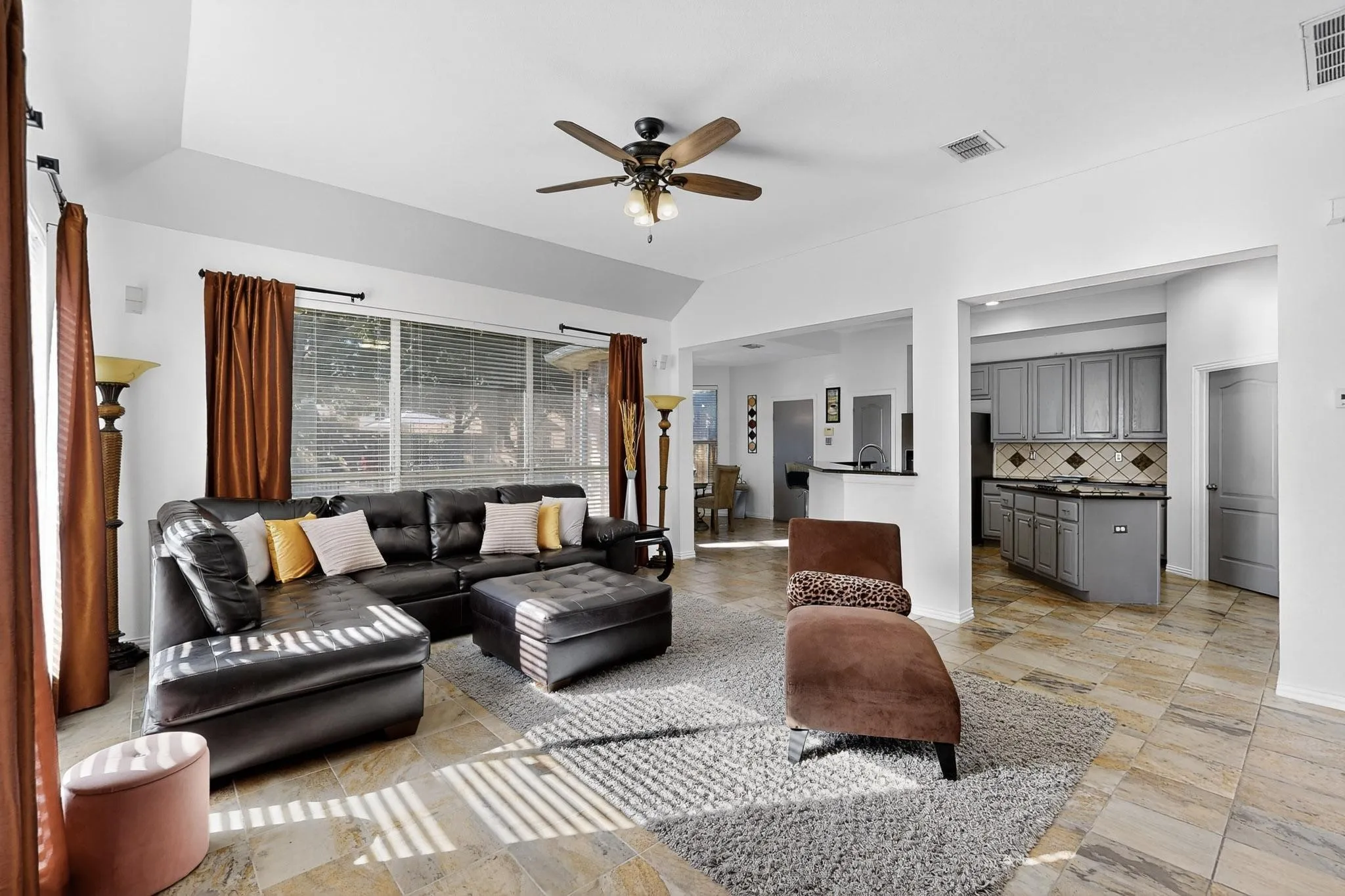Open-concept living space featuring vaulted ceilings, a ceiling fan, and large windows with blinds