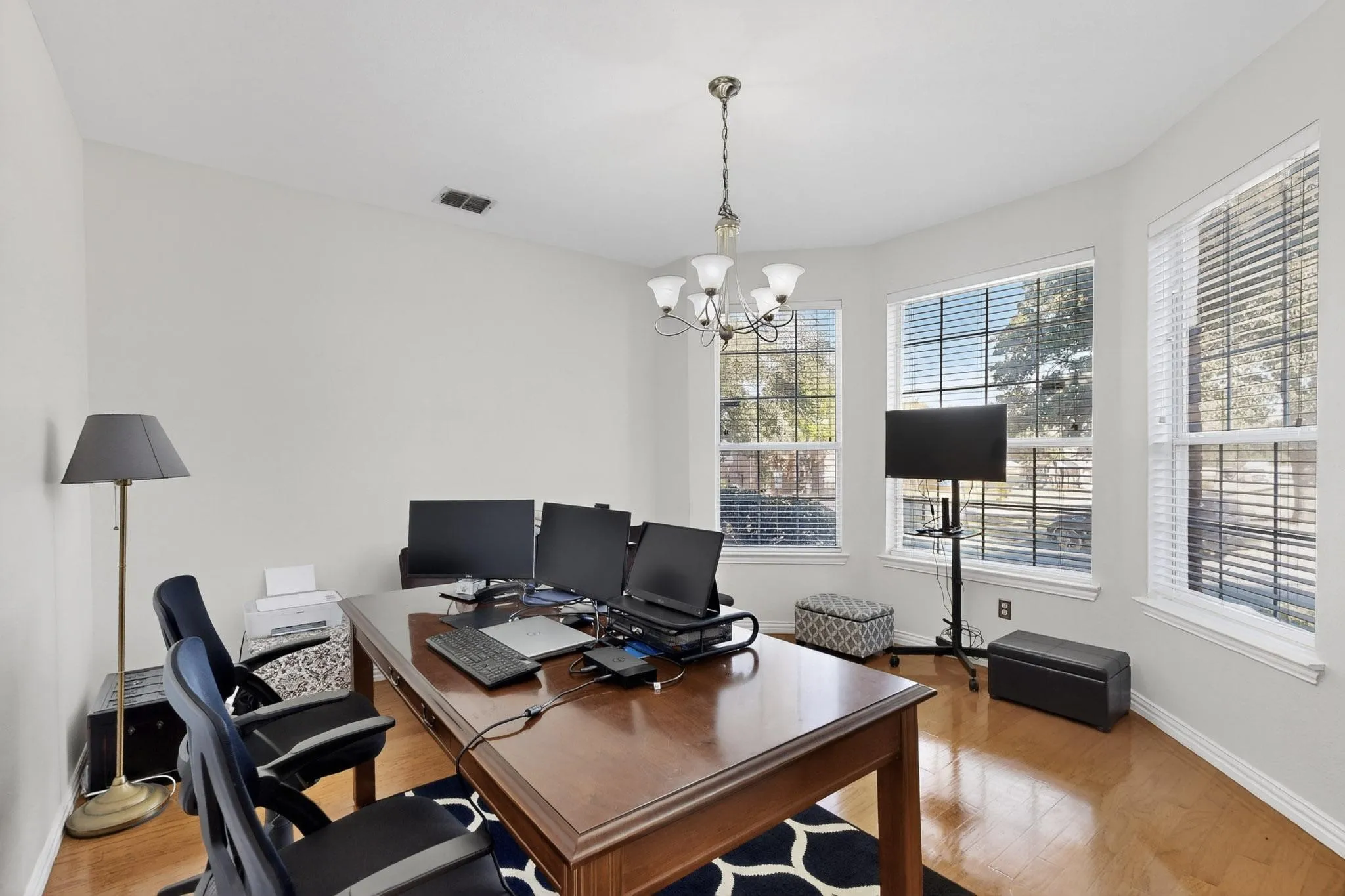 Bright room featuring abundant natural light from multiple windows, recessed ceiling lighting, a chandelier light fixture, and wood-finish flooring