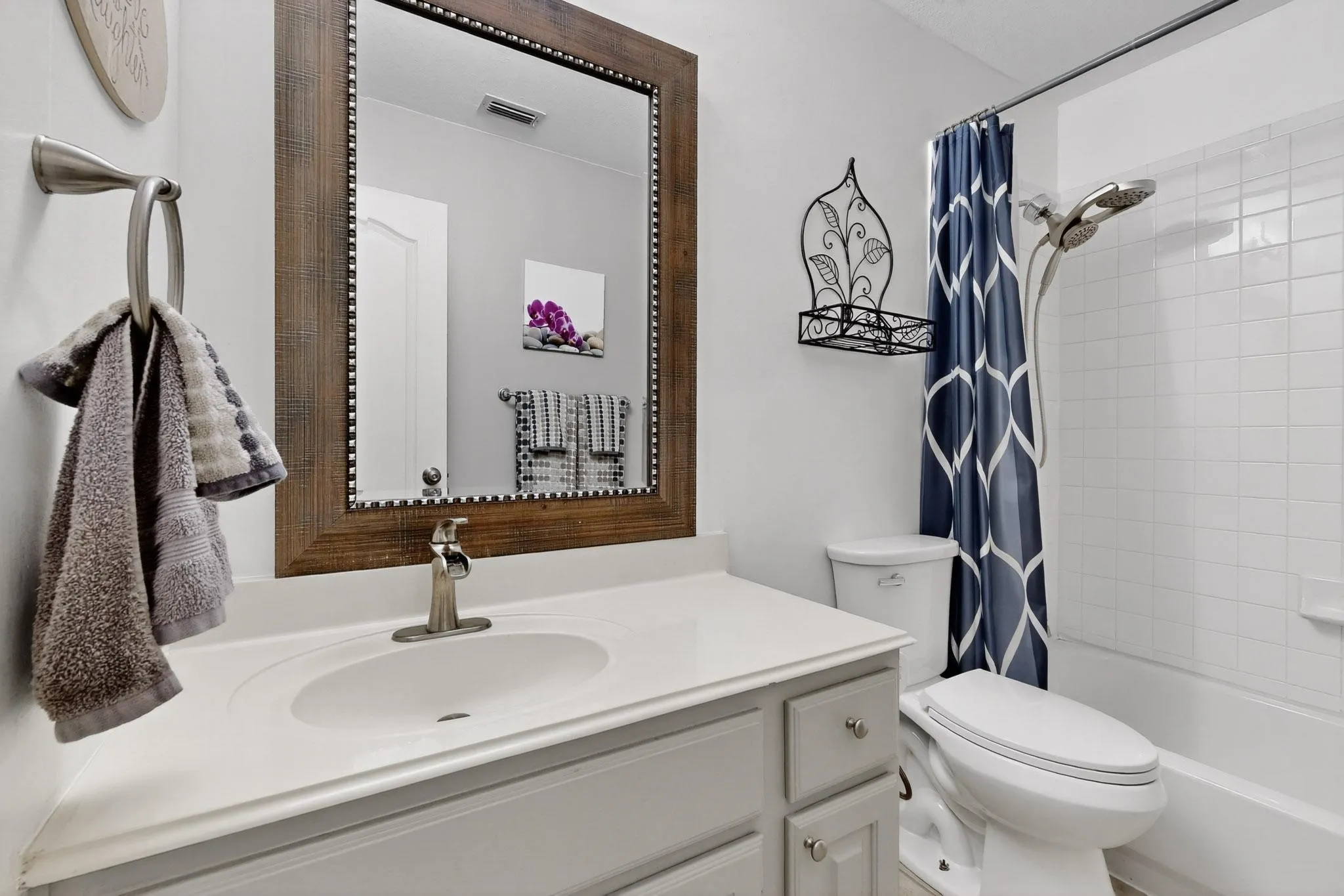 Bathroom featuring a spacious vanity with an integrated sink, brushed nickel faucet, and a large mirror with a decorative wood-finish frame