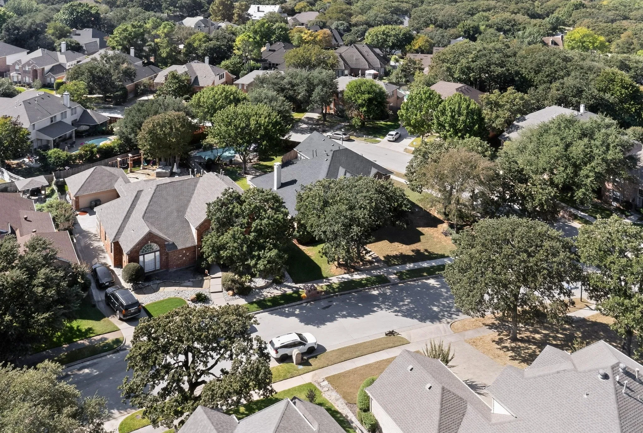 Residential neighborhood with mature trees and a mix of single-family homes, including properties with private pools
