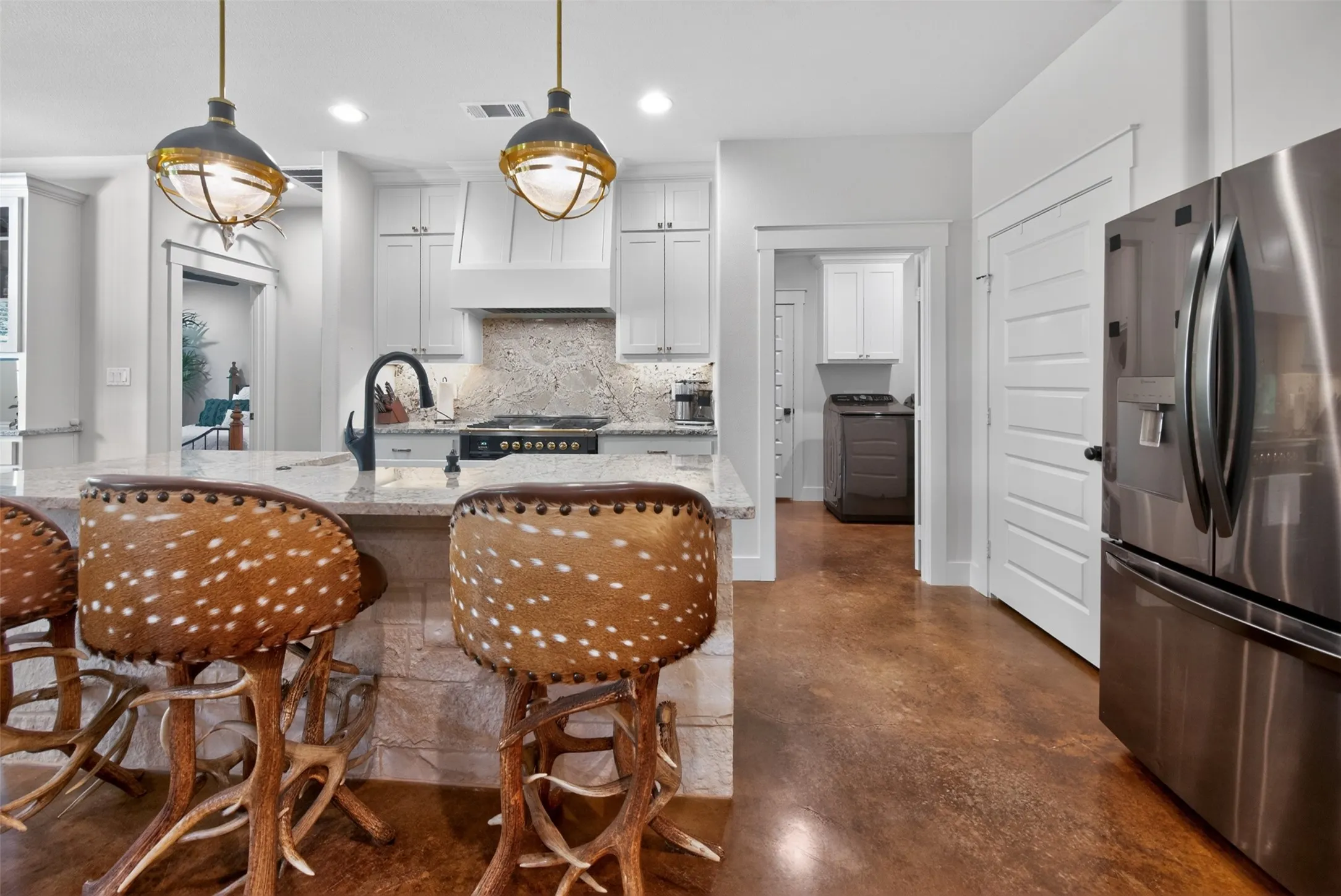 The kitchen features a large island with a granite countertop and a stainless steel sink with a black gooseneck faucet