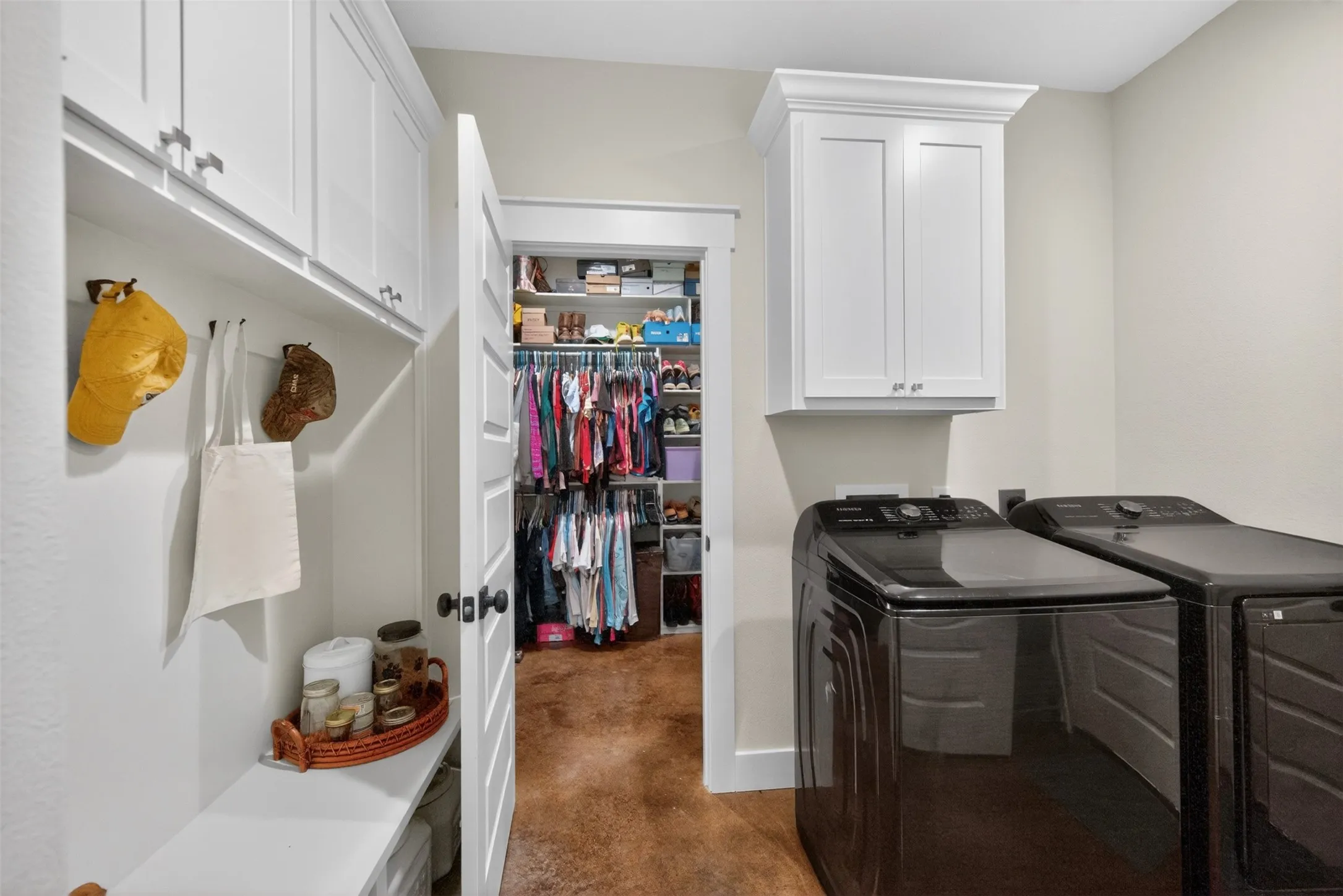 Dedicated utility area featuring white shaker-style cabinetry, a built-in bench with storage, and a deep walk-in closet with custom shelving