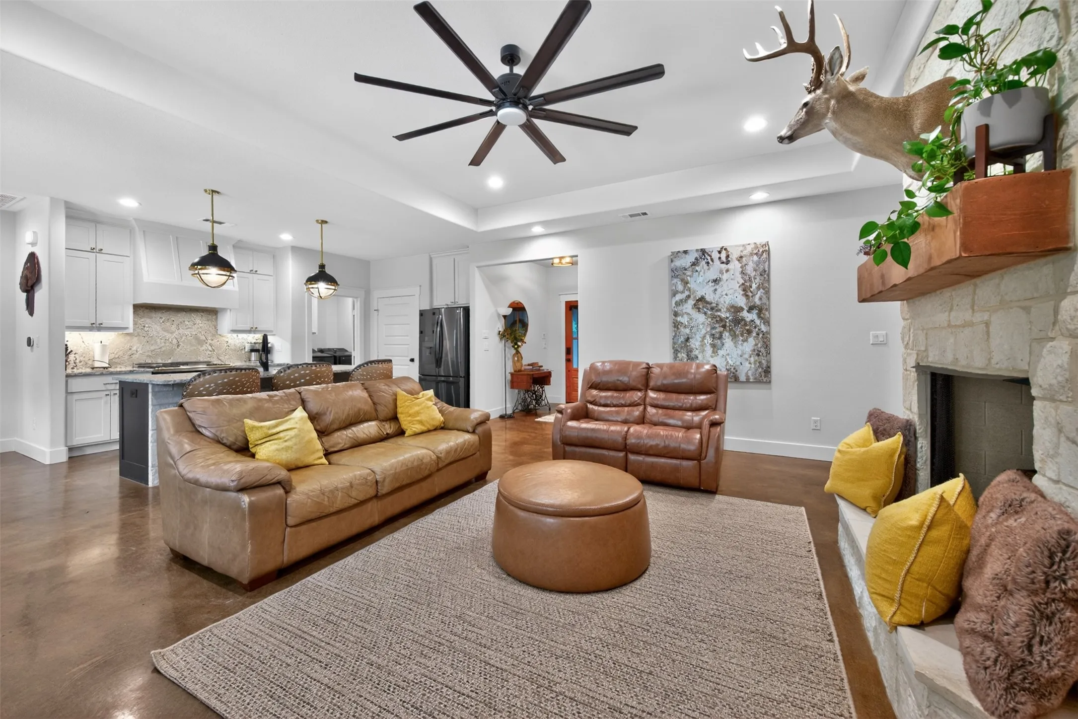 The open-concept living area features a stone-clad fireplace, a ceiling fan, and recessed lighting