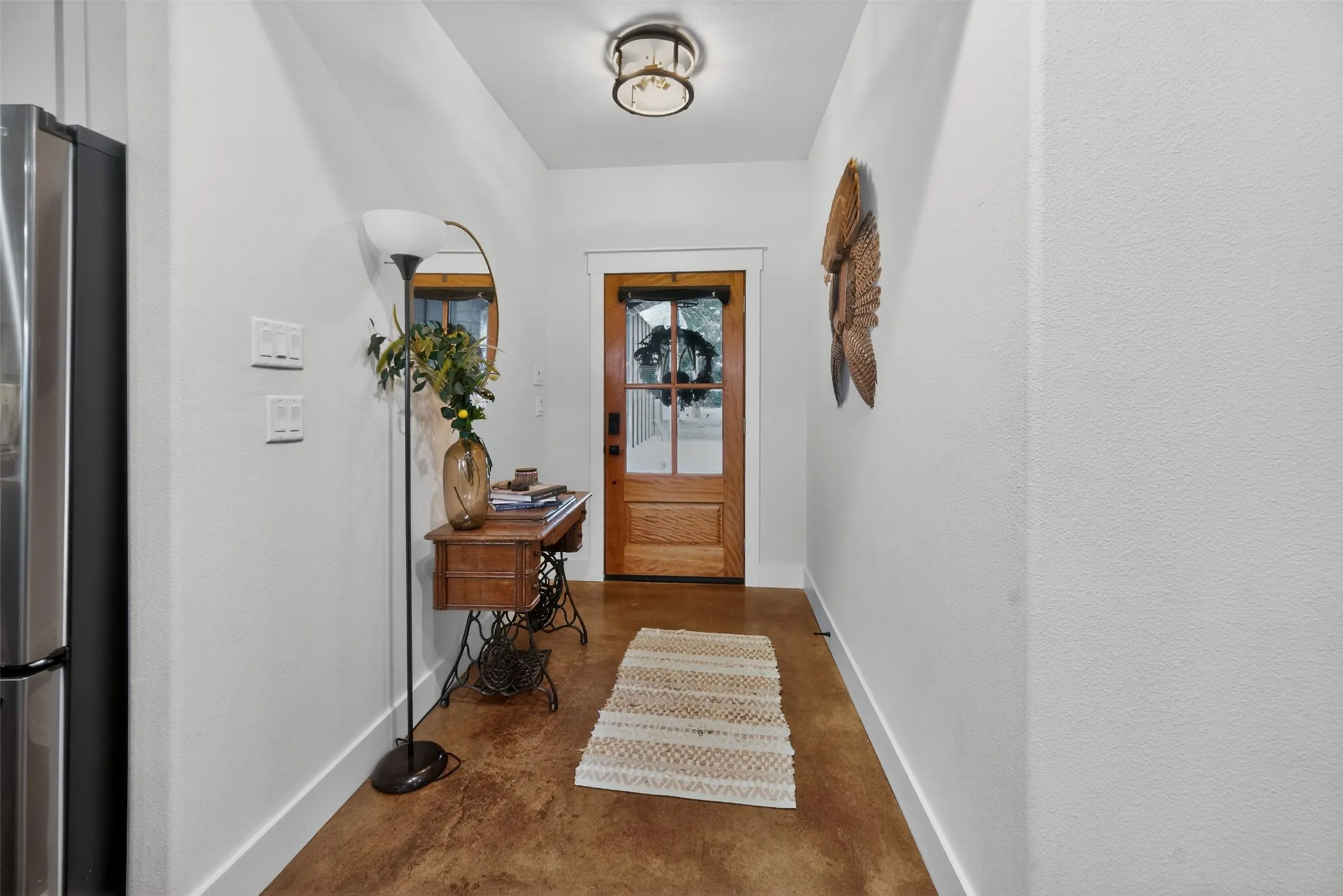 Entryway featuring warm-toned flooring, a light wood door with glass panes, and a contemporary ceiling light fixture