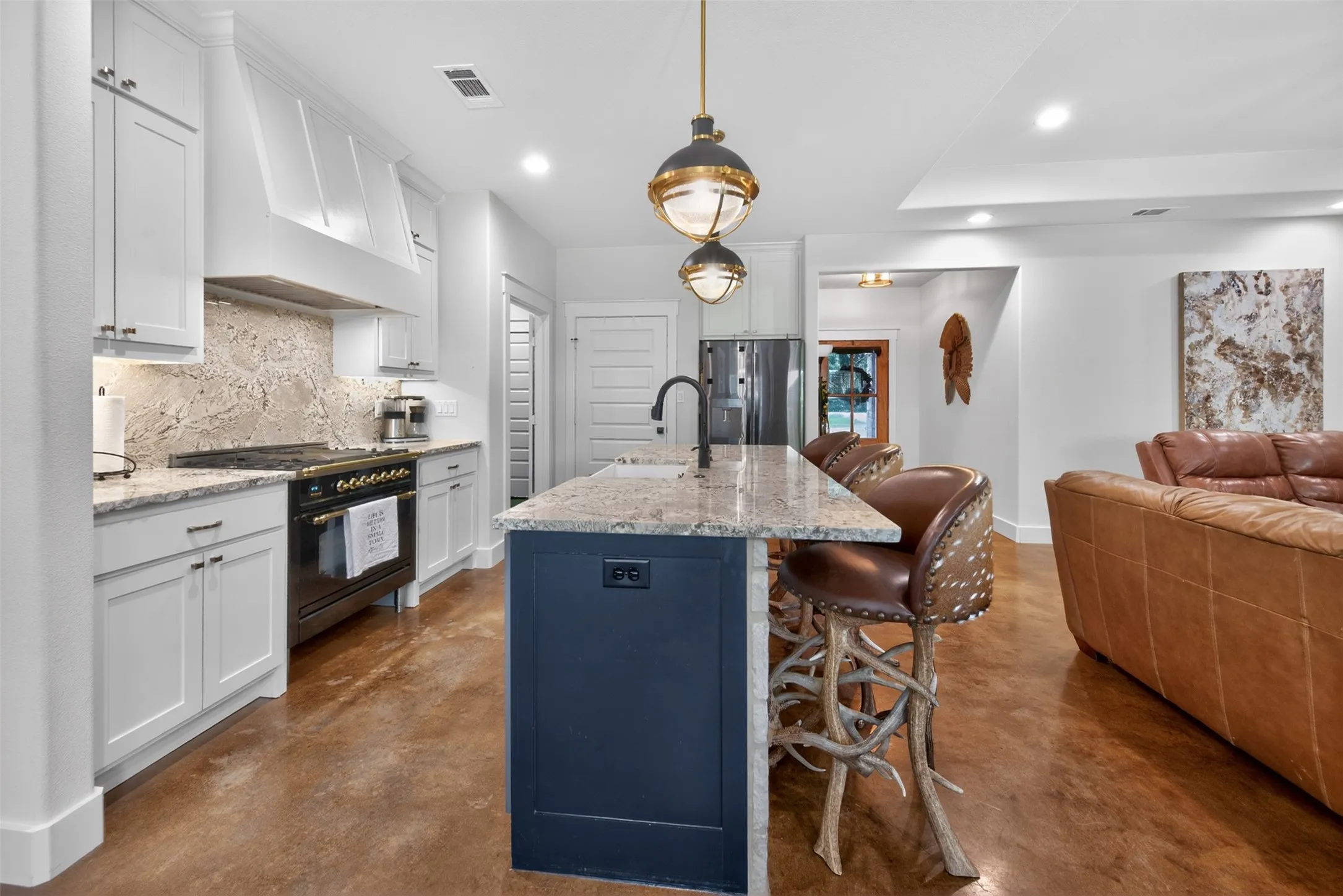 The kitchen features white cabinetry, a dark blue island with a light-colored countertop, and a ILVE high end range