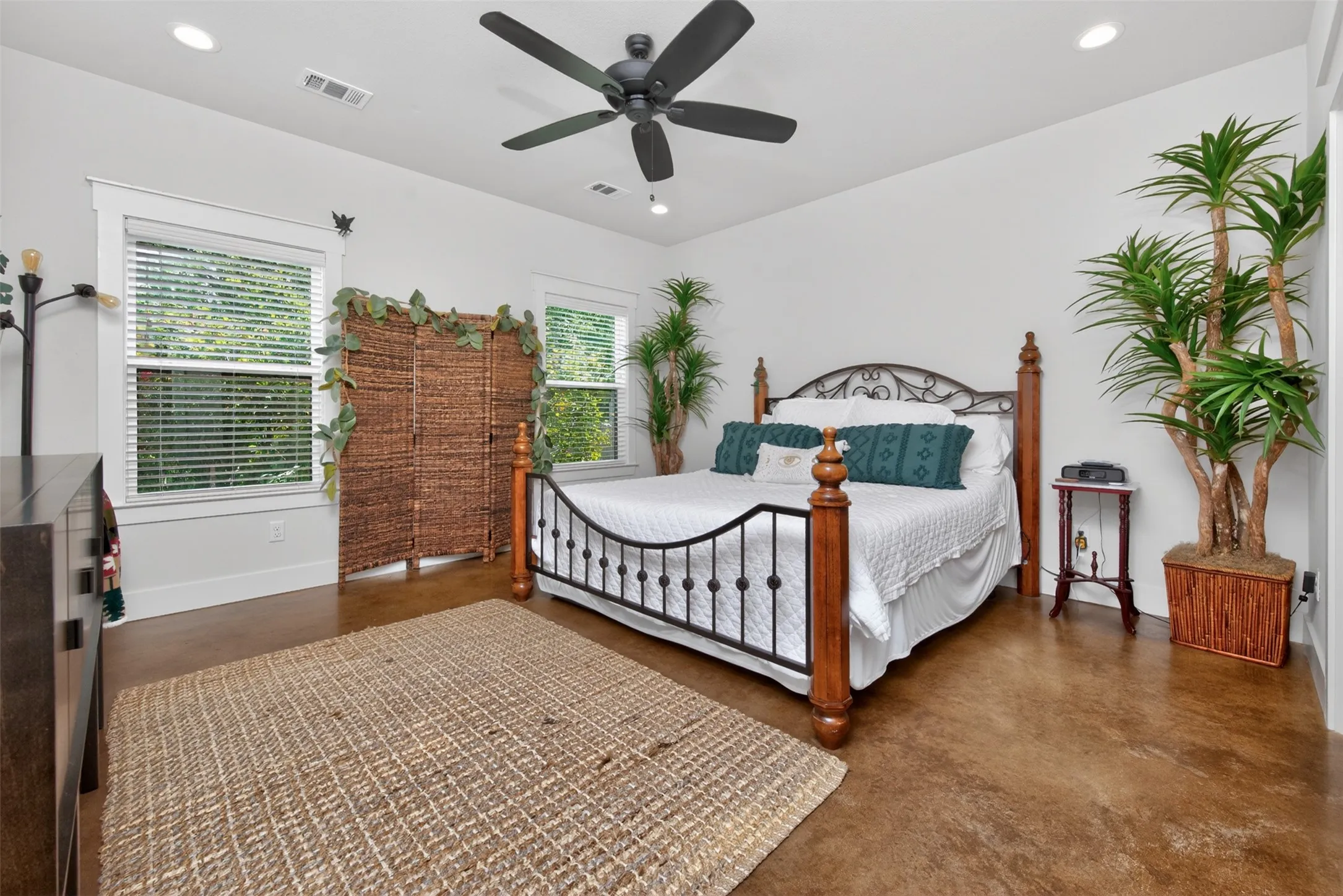 This bedroom features a ceiling fan, recessed lighting, and two windows providing natural light