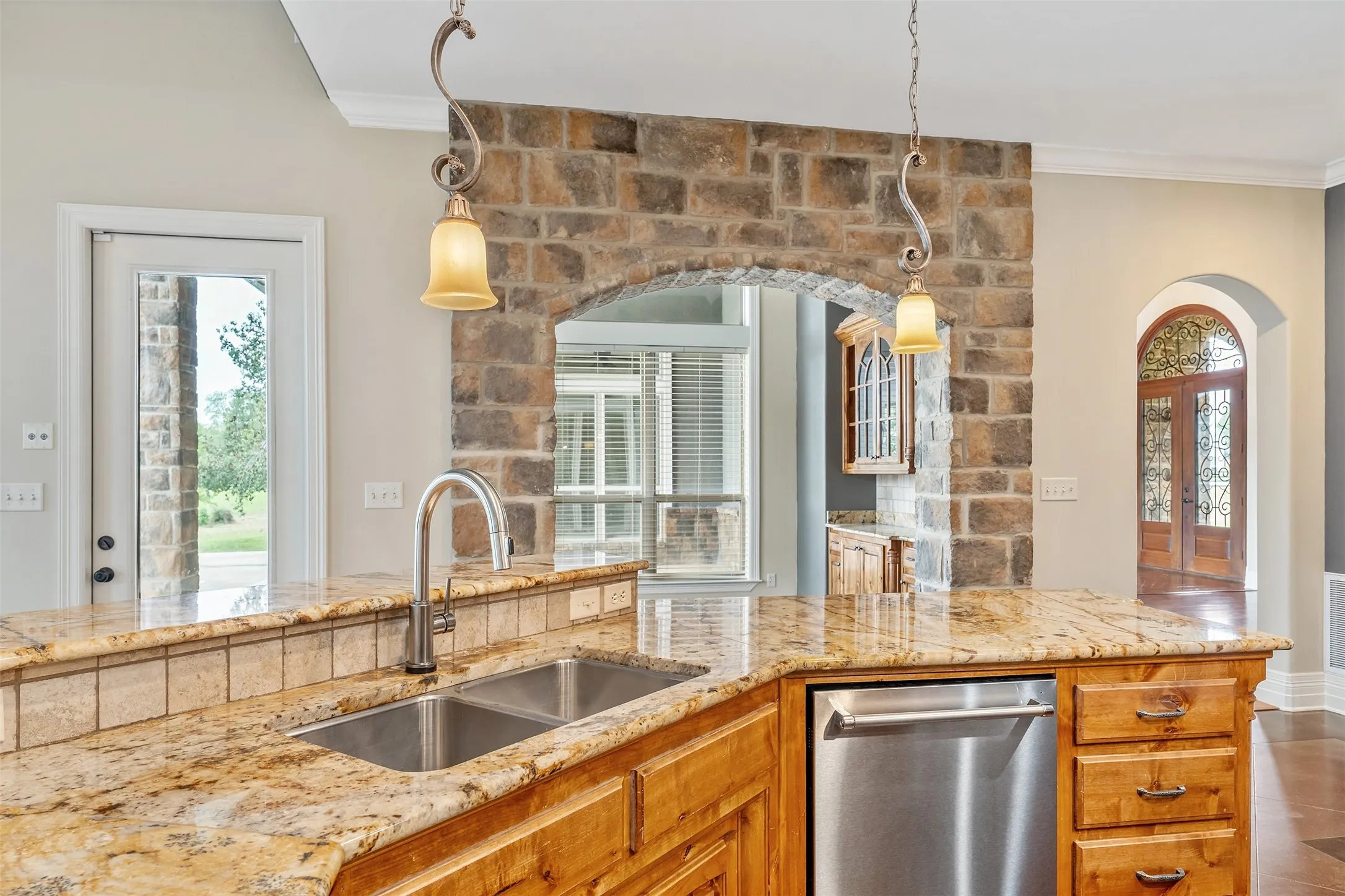 Kitchen island featuring a double basin stainless steel sink, granite countertop, and tiled backsplash