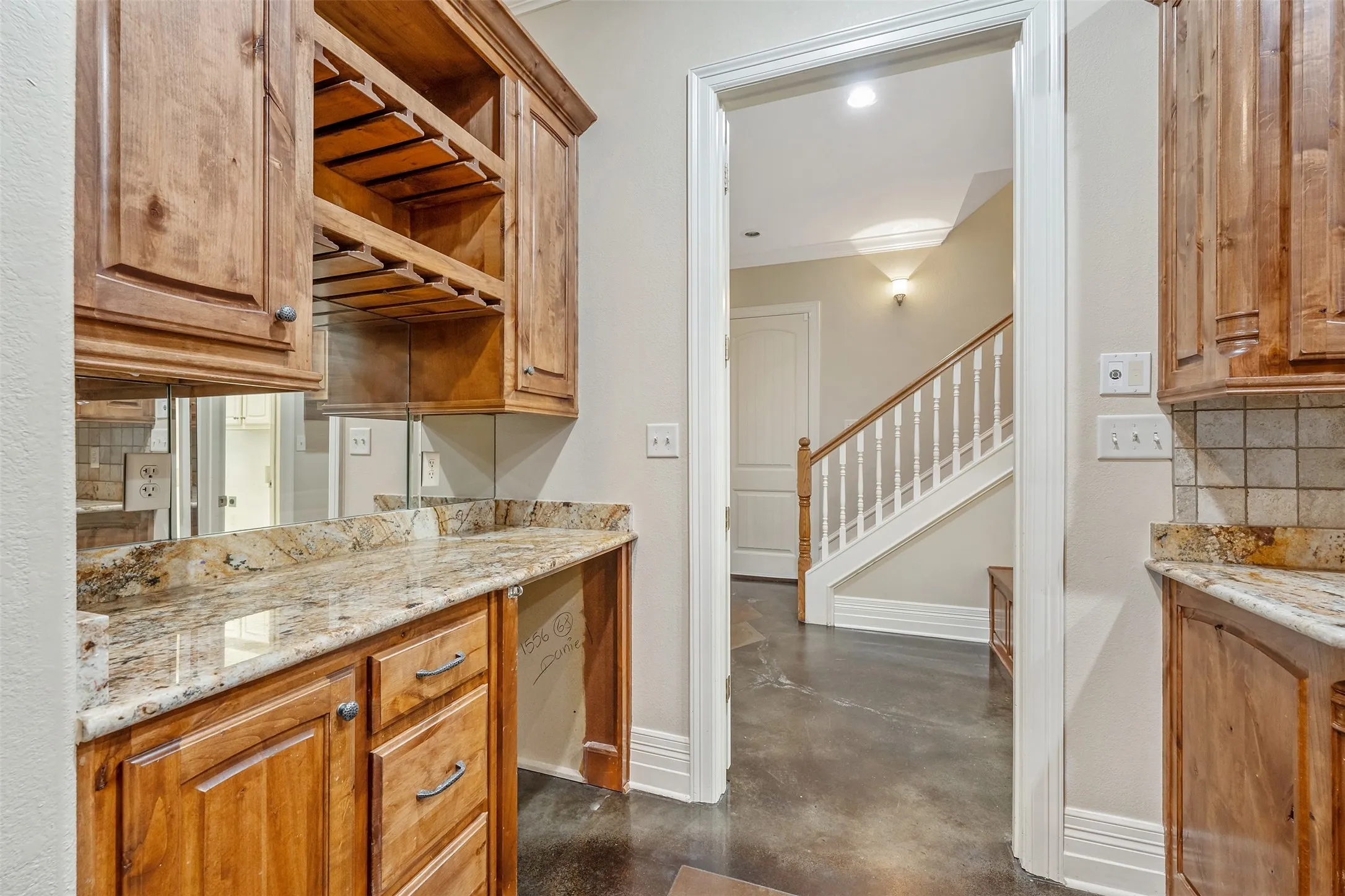 Wet bar featuring wood cabinetry, granite countertops, and a mirrored backsplash