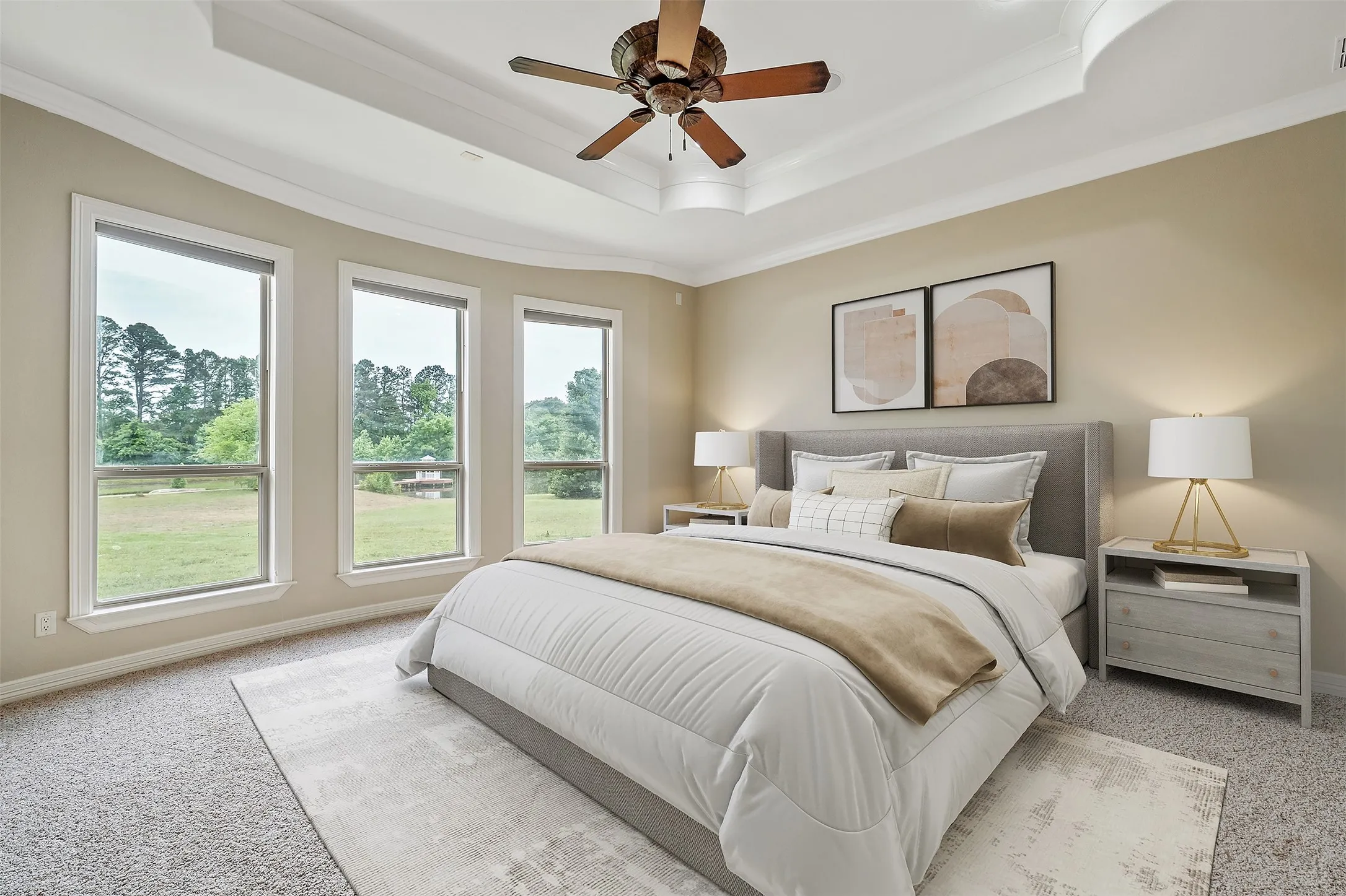 Tray ceiling with crown molding, three large windows, and a ceiling fan