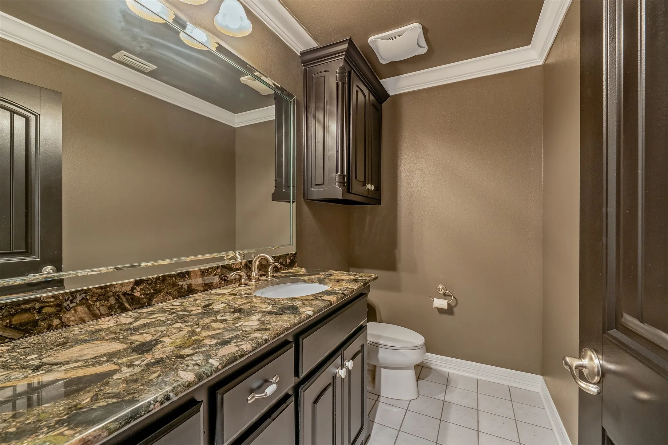 Vanity area featuring a stone countertop with an undermount sink, dark wood cabinetry, and a full-width mirror