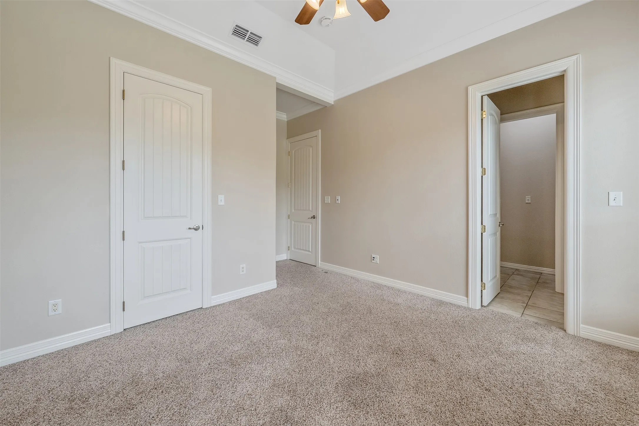 Carpeted room featuring a ceiling fan, white trim, and doors with panel detailing