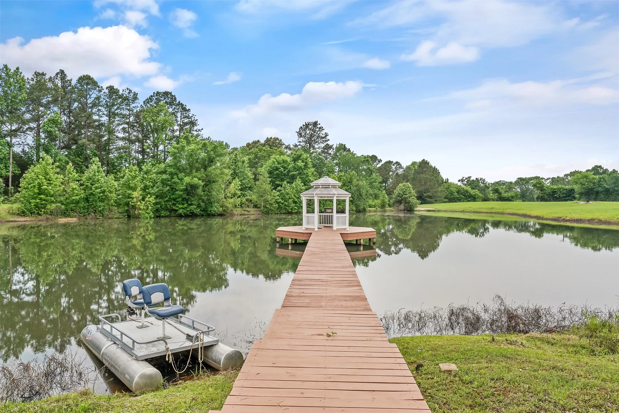 Expansive pond with a wooden dock leading to a white gazebo