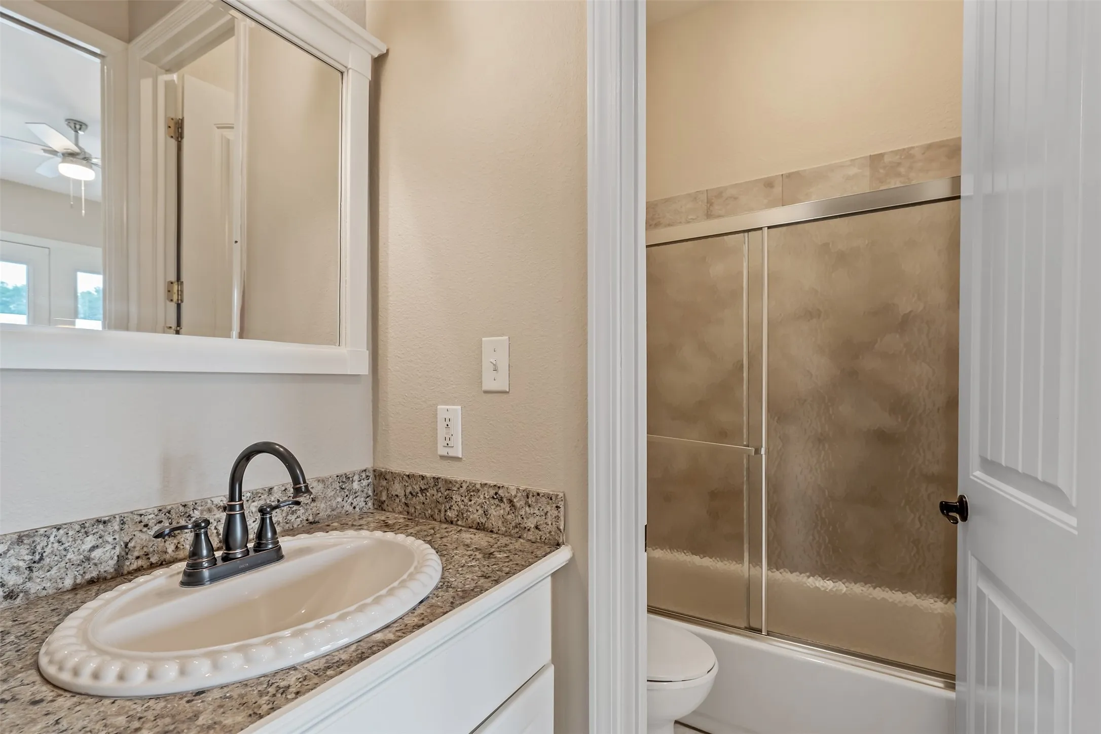 Bathroom vanity with a granite countertop, undermount sink, and dark bronze faucet