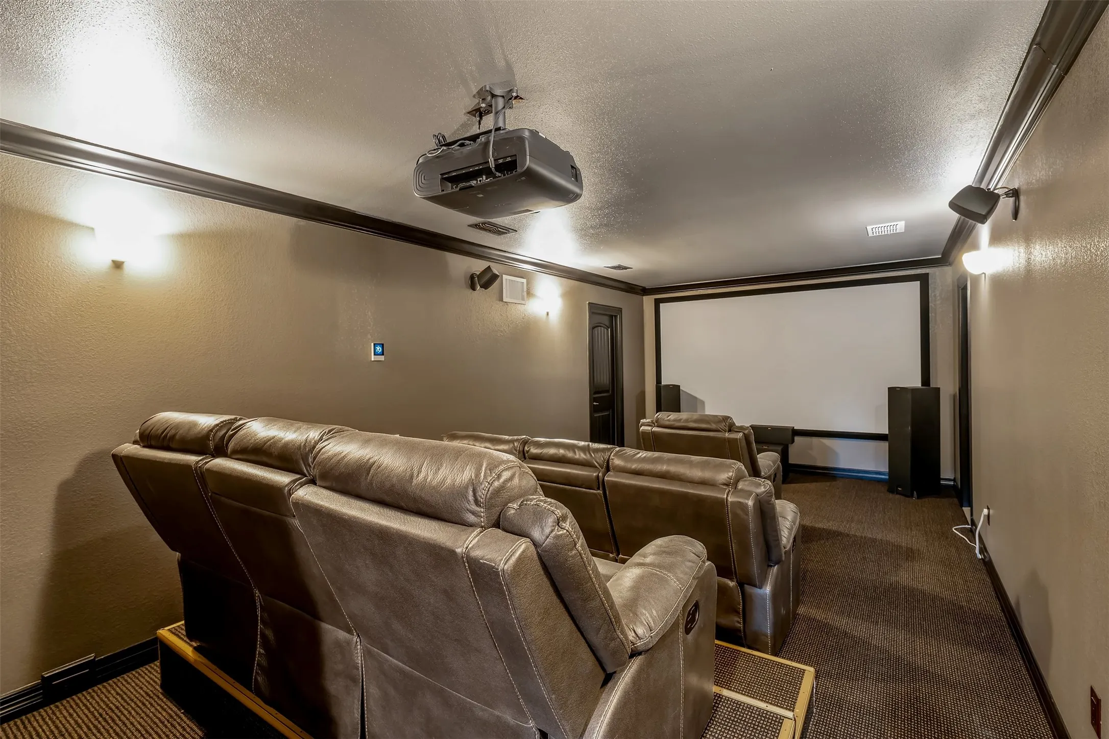 Dedicated media room with tiered seating featuring projector, large screen, and integrated speakers
