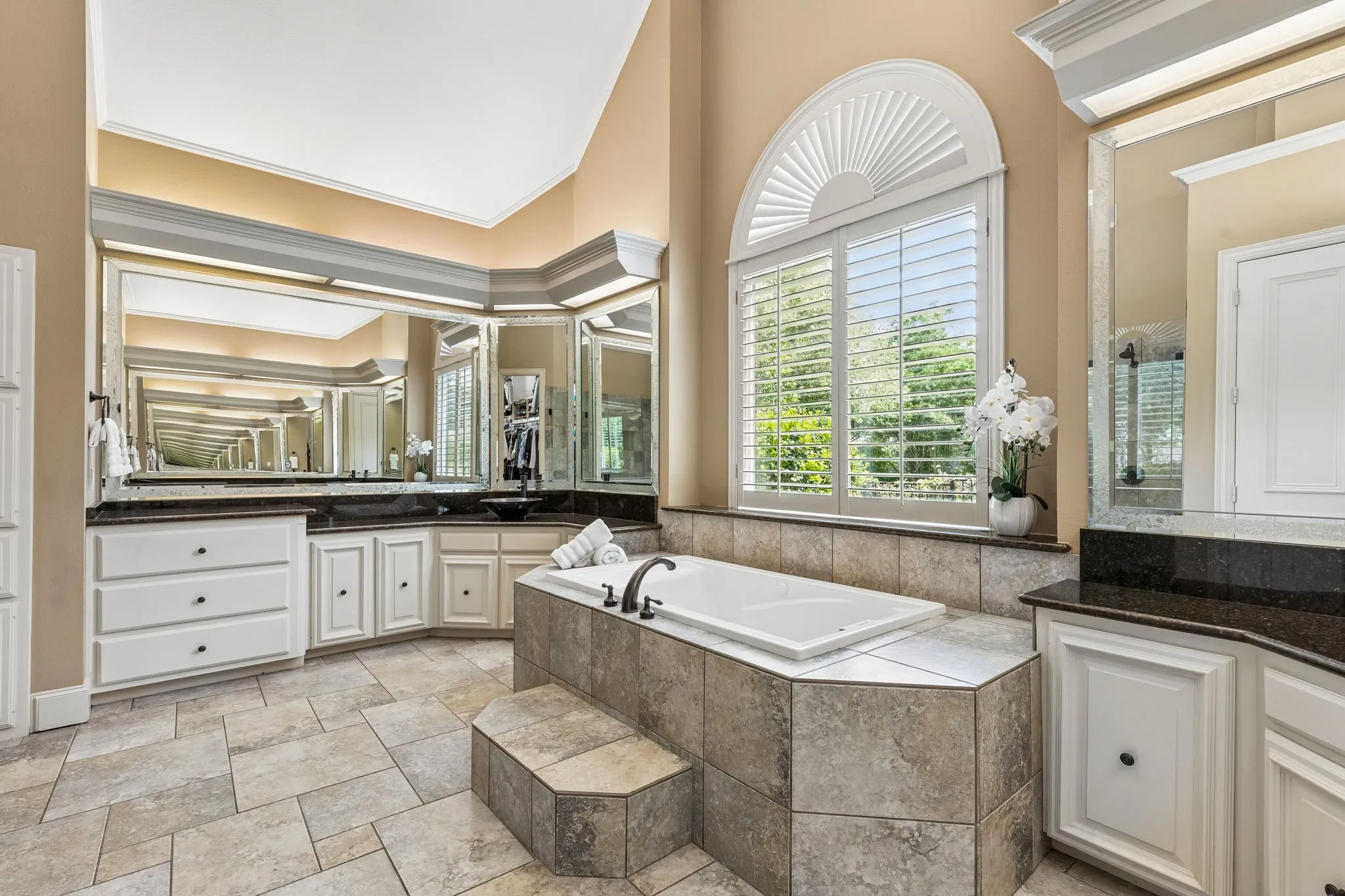 Primary spa bath with extensive counter space, separate vanities, vaulted ceilings, and frameless glass walk-in shower.