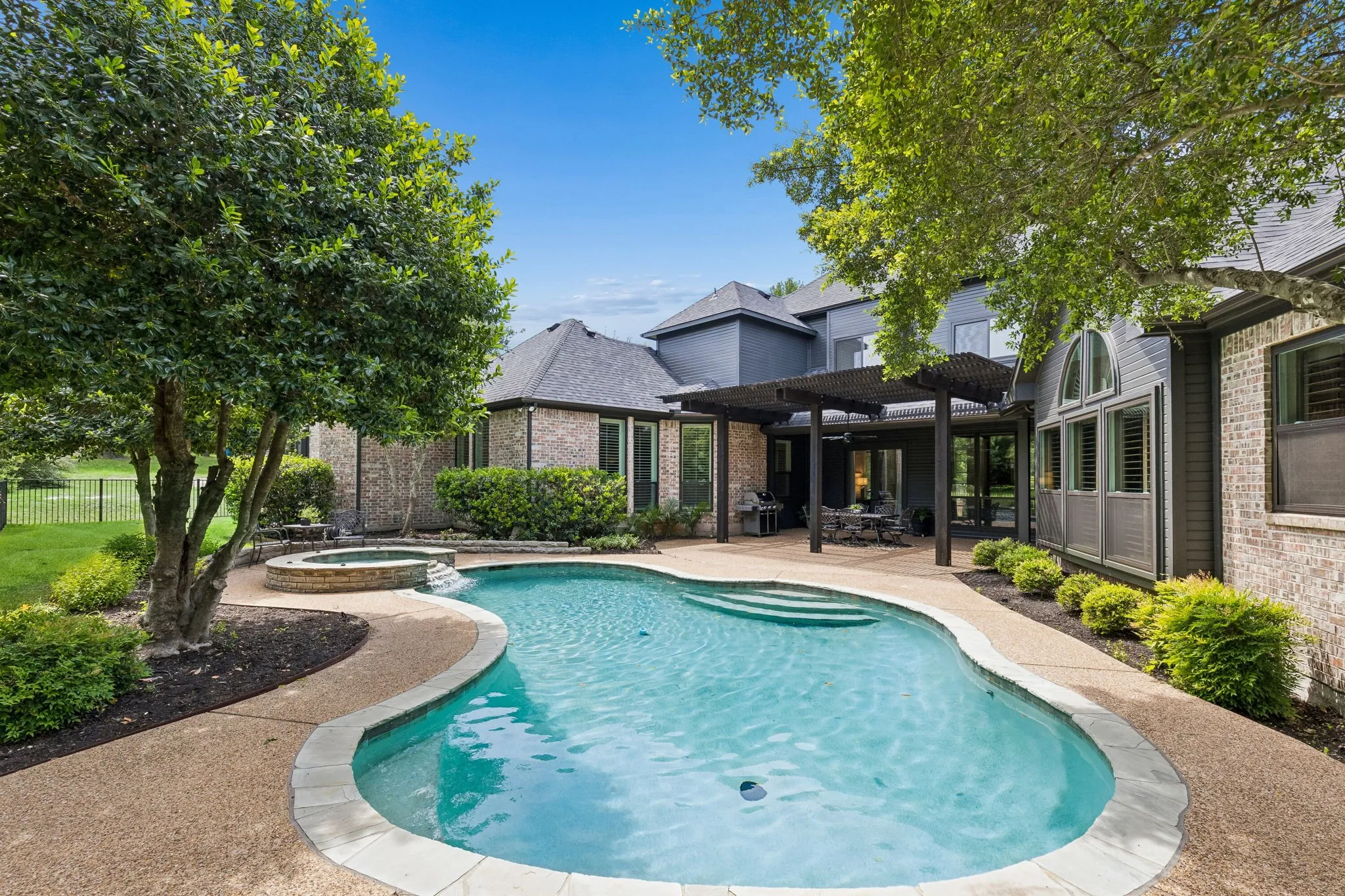 Backyard retreat with pool, patio, and multiple areas to relax or entertain surrounded by mature trees for complete privacy.