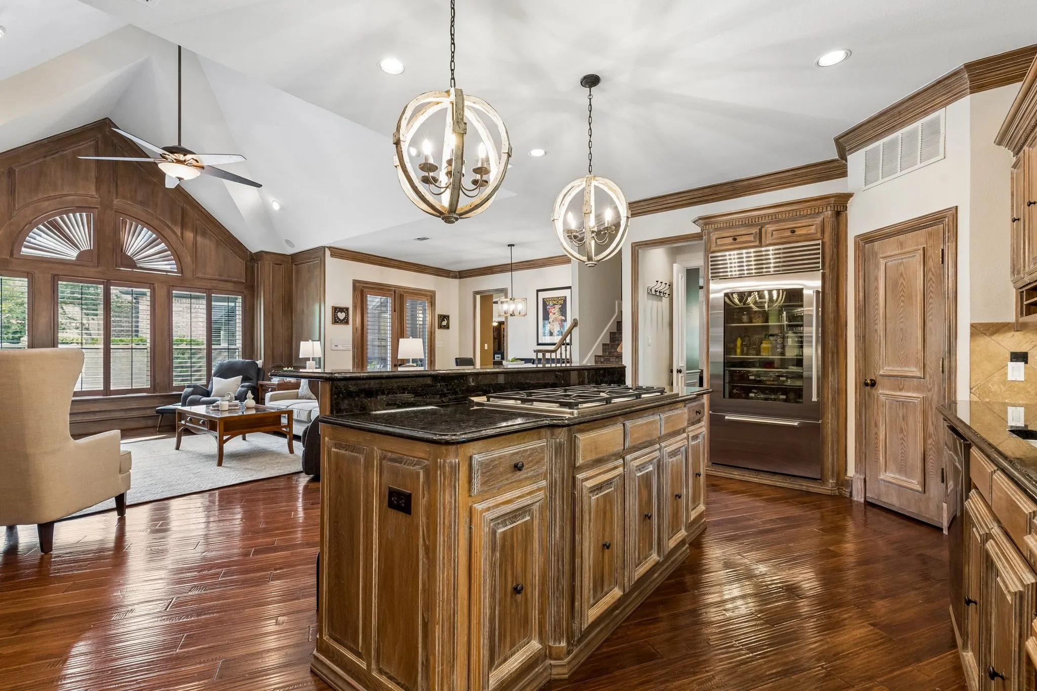 Gourmet kitchen featuring a large center island with extensive prep and serving space, breakfast bar seating, commercial-grade 6-burner gas range, Sub-Zero refrigerator, double ovens, and walk-in pantry.