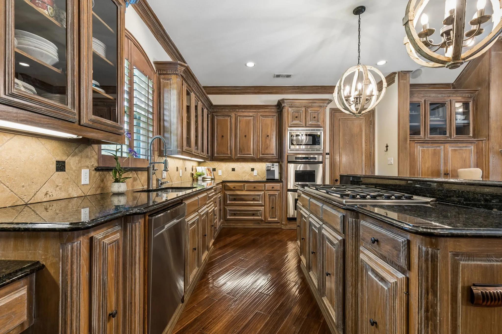Gourmet kitchen featuring a large center island with extensive prep and serving space, breakfast bar seating, commercial-grade 6-burner gas range, Sub-Zero refrigerator, double ovens, and walk-in pantry.