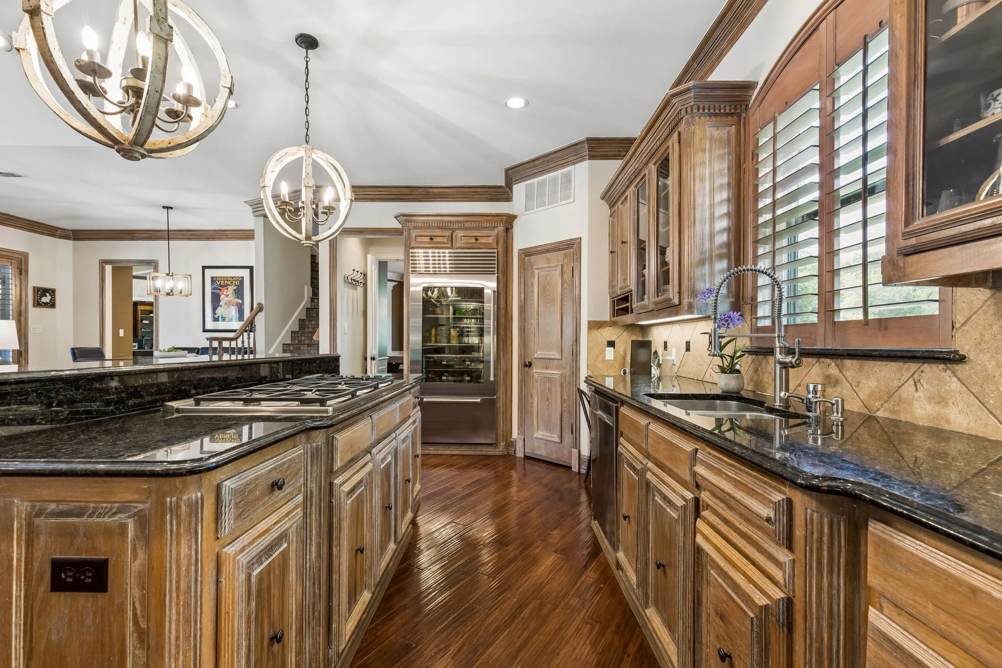 Gourmet kitchen featuring a large center island with extensive prep and serving space, breakfast bar seating, commercial-grade 6-burner gas range, Sub-Zero refrigerator, double ovens, and walk-in pantry.